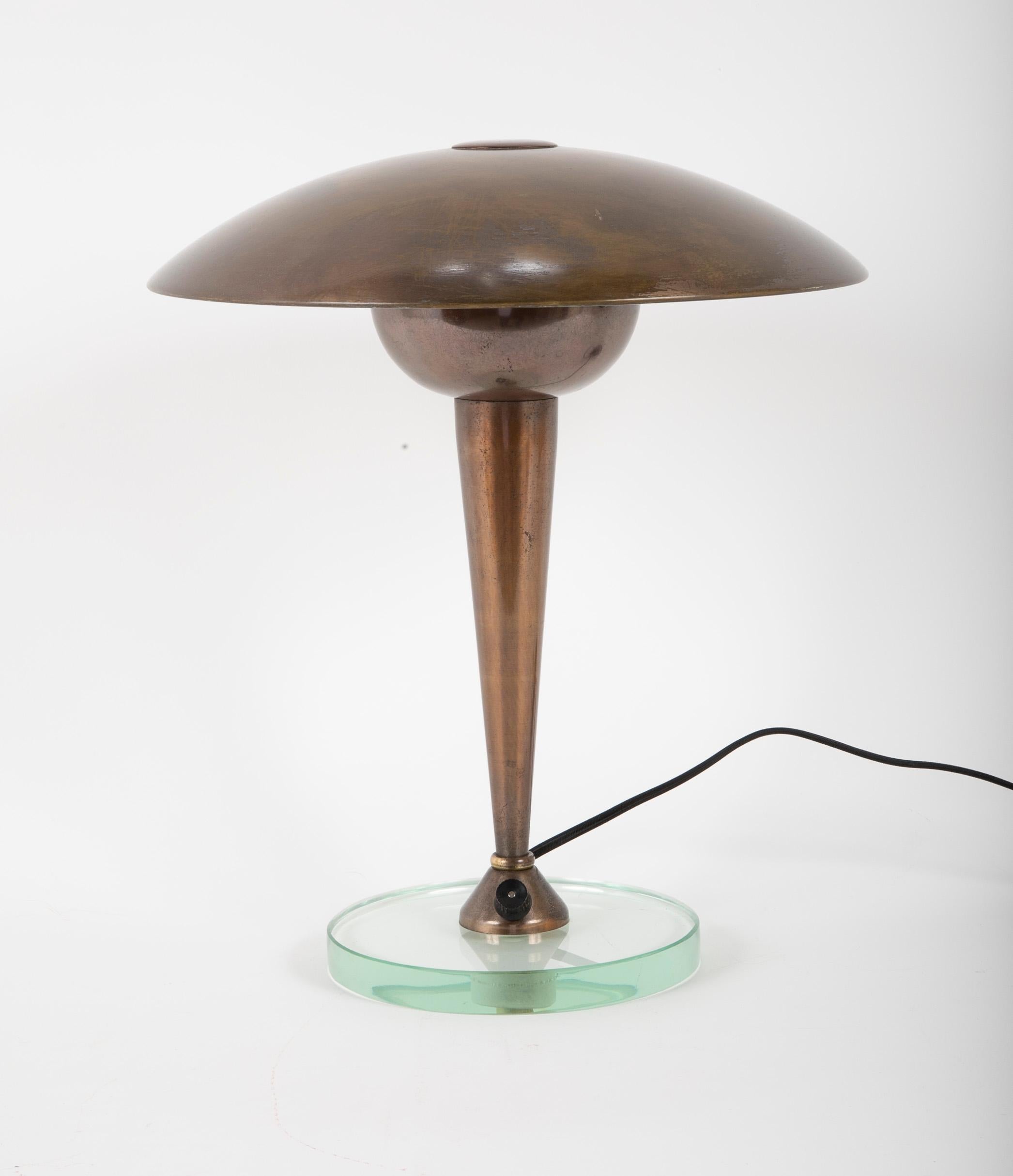 A lamp produced by Stilnovo, brass shade on a conical brass central shaft rising from a round piece of 3/4