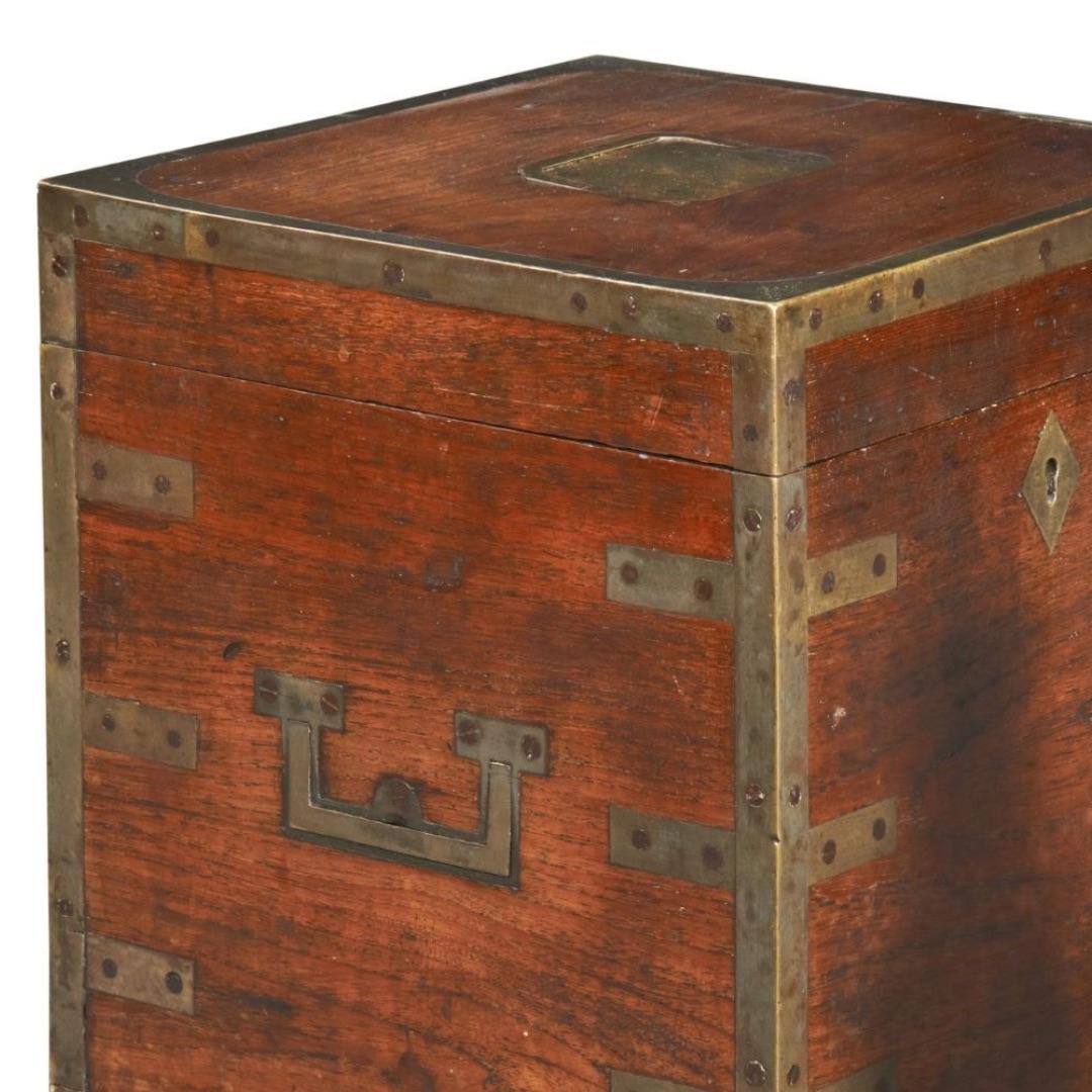 A brass bound Anglo-Indian teak Decanter Box for 4 bottles. The Box is well made with both brass edging and straps screwed on. To the sides are skeletal campaign handles and the escutcheon is a diamond shape. The box has a key. The interior has