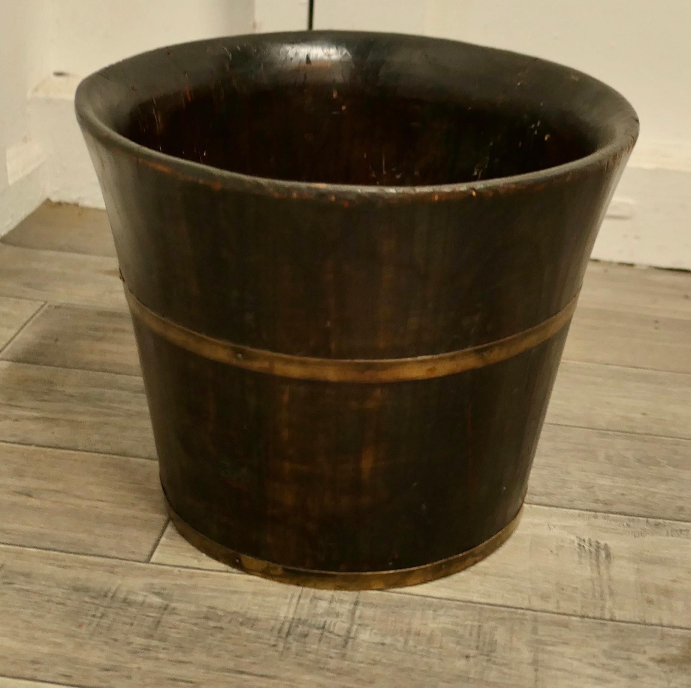 A brass bound wooden planter.

This lovely old piece is made in dark pine and brass banding 
A very attractive planter or a very superior waste paper basket?
The Barrel is 10” high and 12 in diameter.
TJK229.