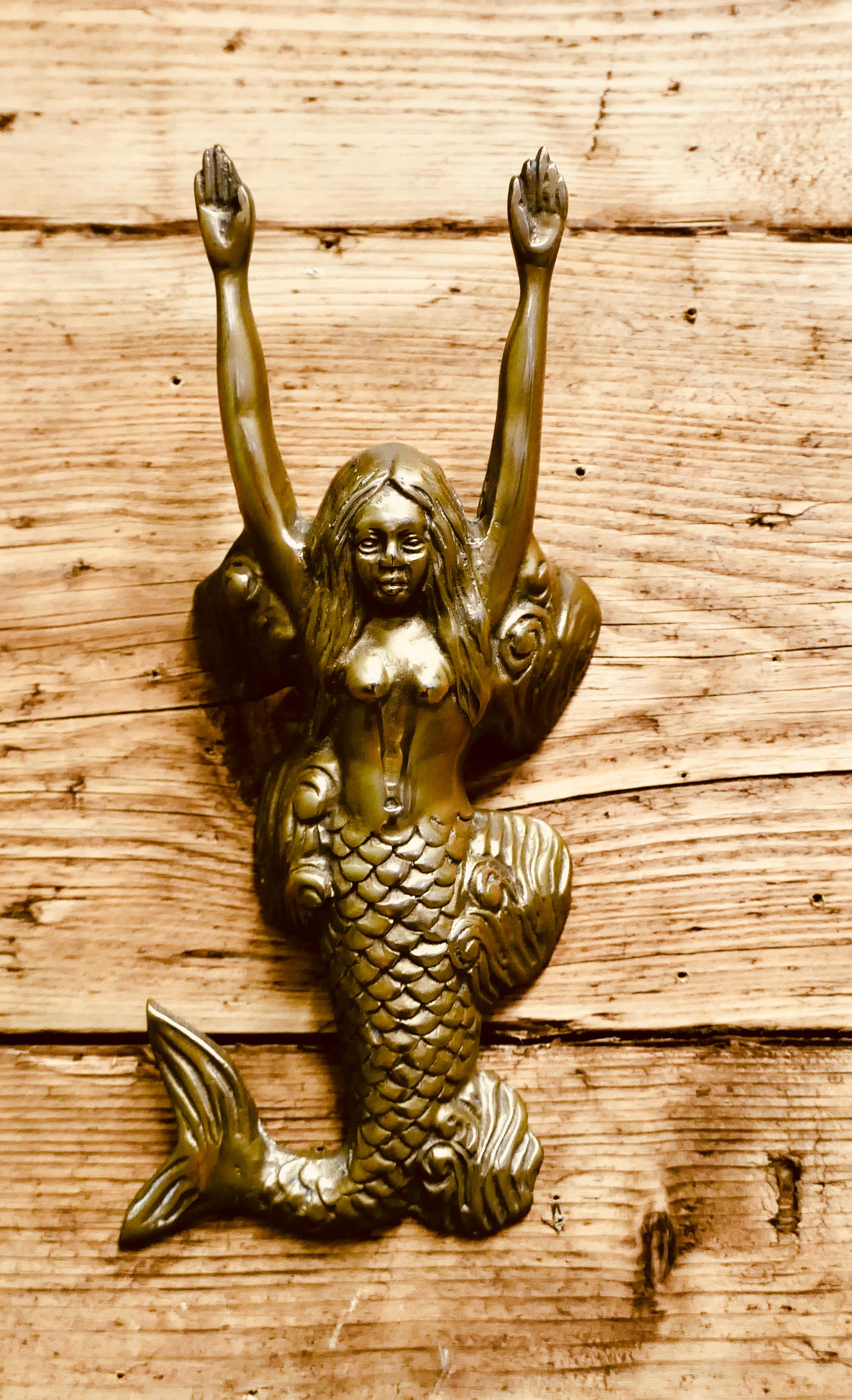 A Brass Door Knocker in the Shape of a Mermaid

This is an unusual door knocker, it is installed by hooking it over 2 screw heads, it is then operated by flicking the mermaid’s body or pushing her arms back
The door knocker is in sound condition it