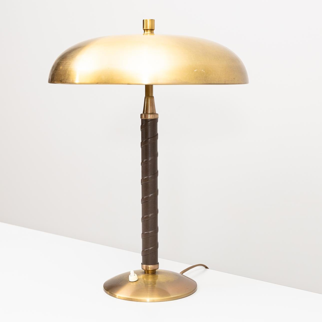 Lampe de table, modèle 5013, par Einar Bäckström, années 1940. Le design présente un abat-jour bombé en laiton associé à une colonne spiralée enveloppée de similicuir, ancrée par une large base circulaire en laiton assorti. Dotée d'une poignée