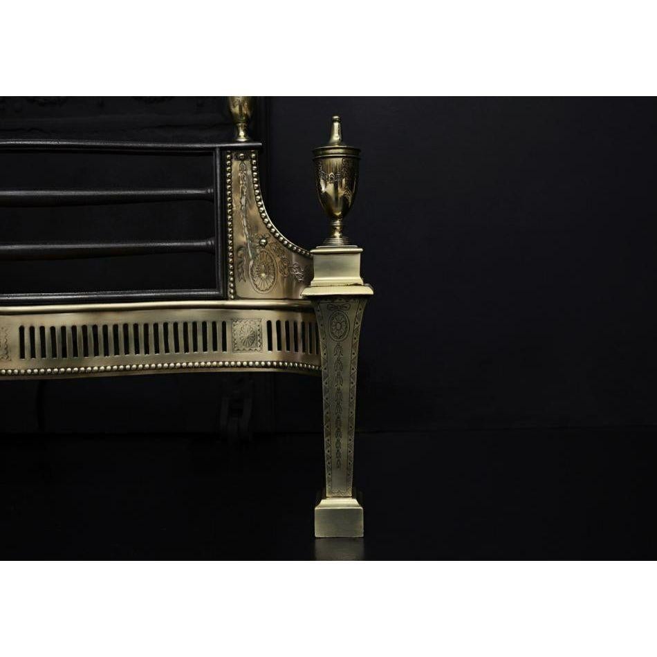 A 19th century brass firegrate in the Georgian manner. The tapering legs engraved with bellflowers and paterae, surmounted by urn finials. The fluted and beaded fret surmounted by bowed cast iron front bars, flanked by decorative side wings. Cast