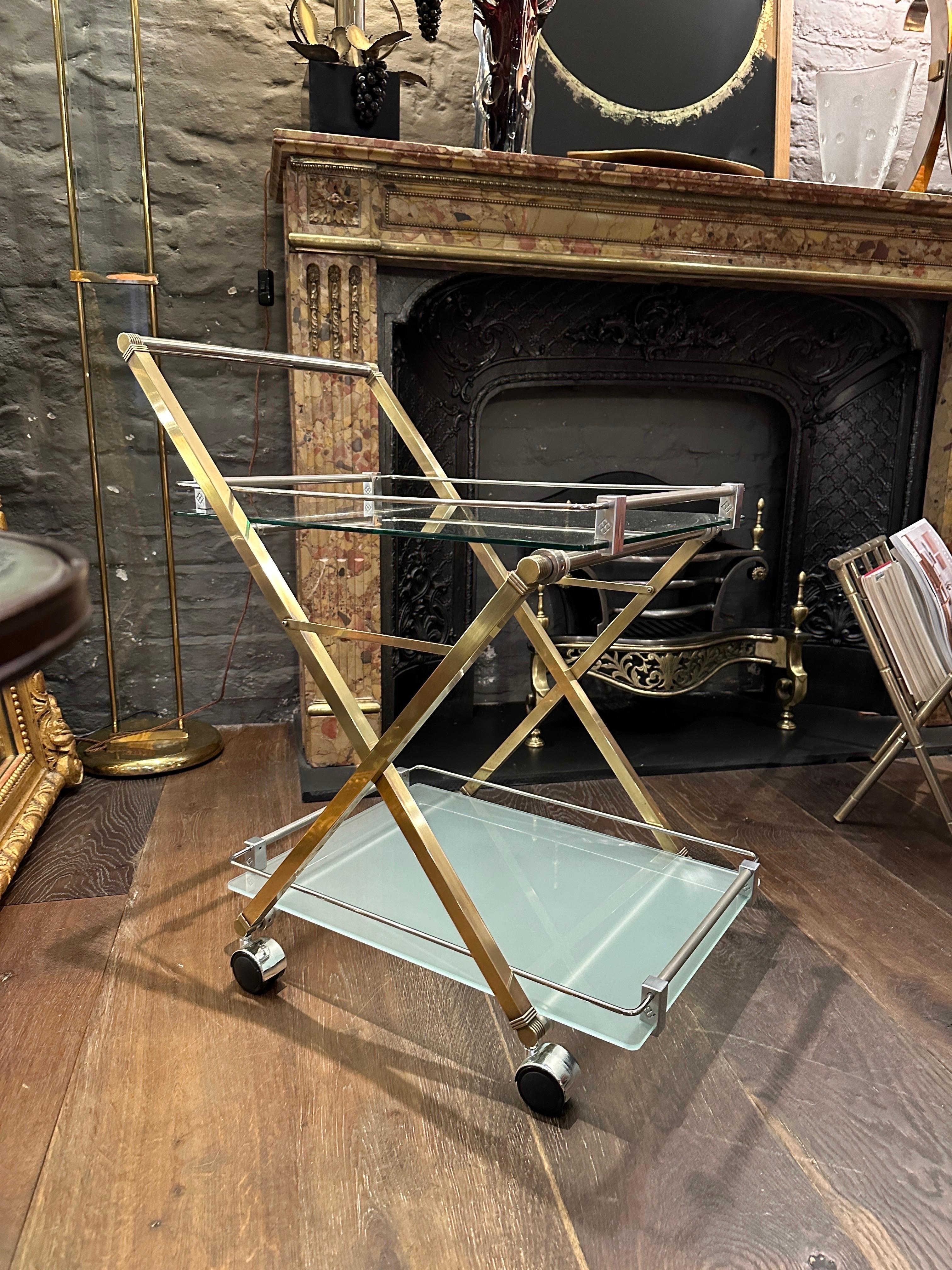 A quality brass and chrome bar cart with two removable trays in glass, the top clear the bottom opaque. Marked with the Ghyczy stamp on each support. The X frame design in brass with the trays and handle in chrome. 