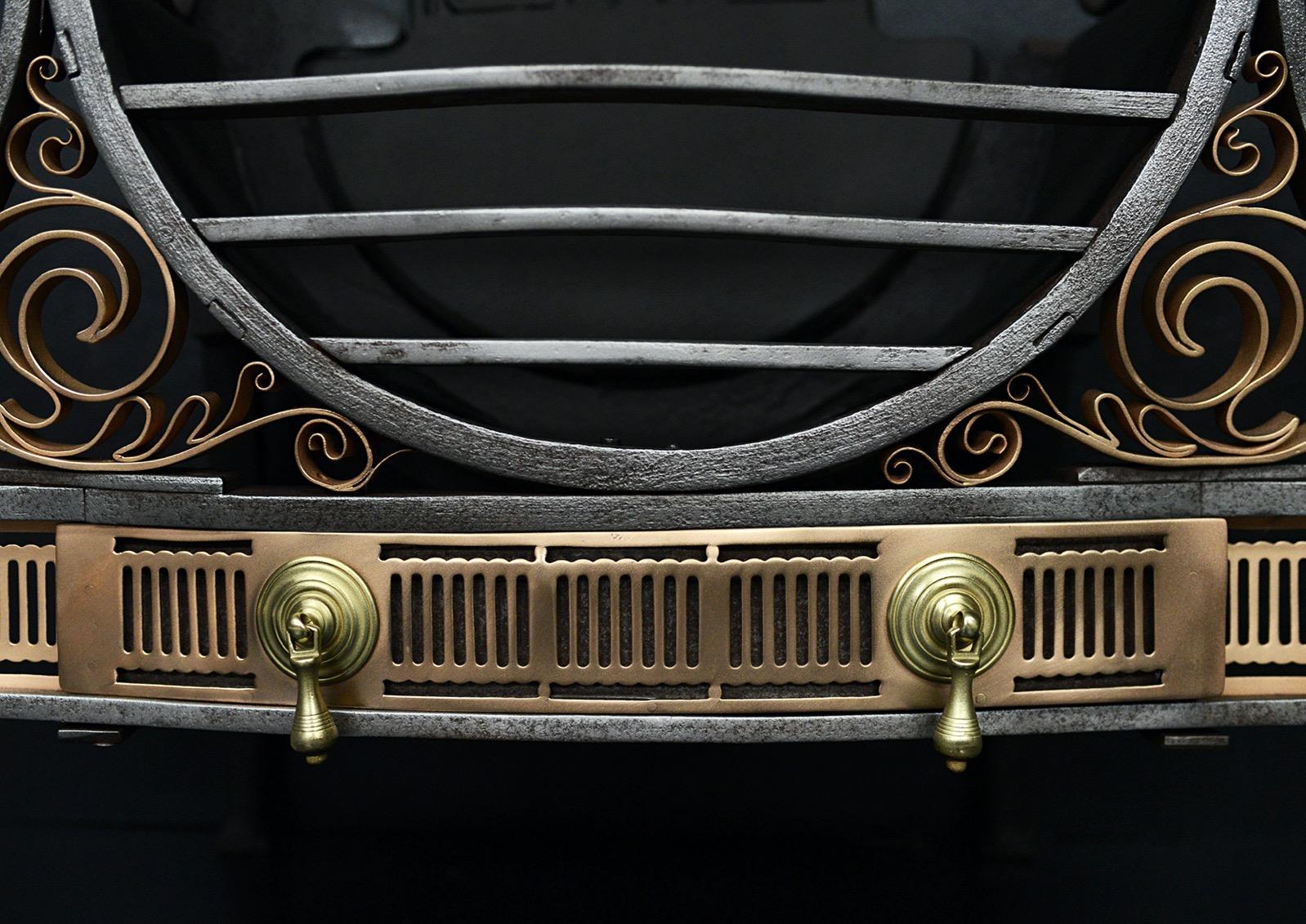 An Arts & Crafts firebasket. The scrolled wrought iron feet surmounted by U-shaped burning area and scrolled finials. Decorative gunmetal scrollwork to sidewings and pierced fluted fret below featuring removable ashpan with brass handles. Decorative