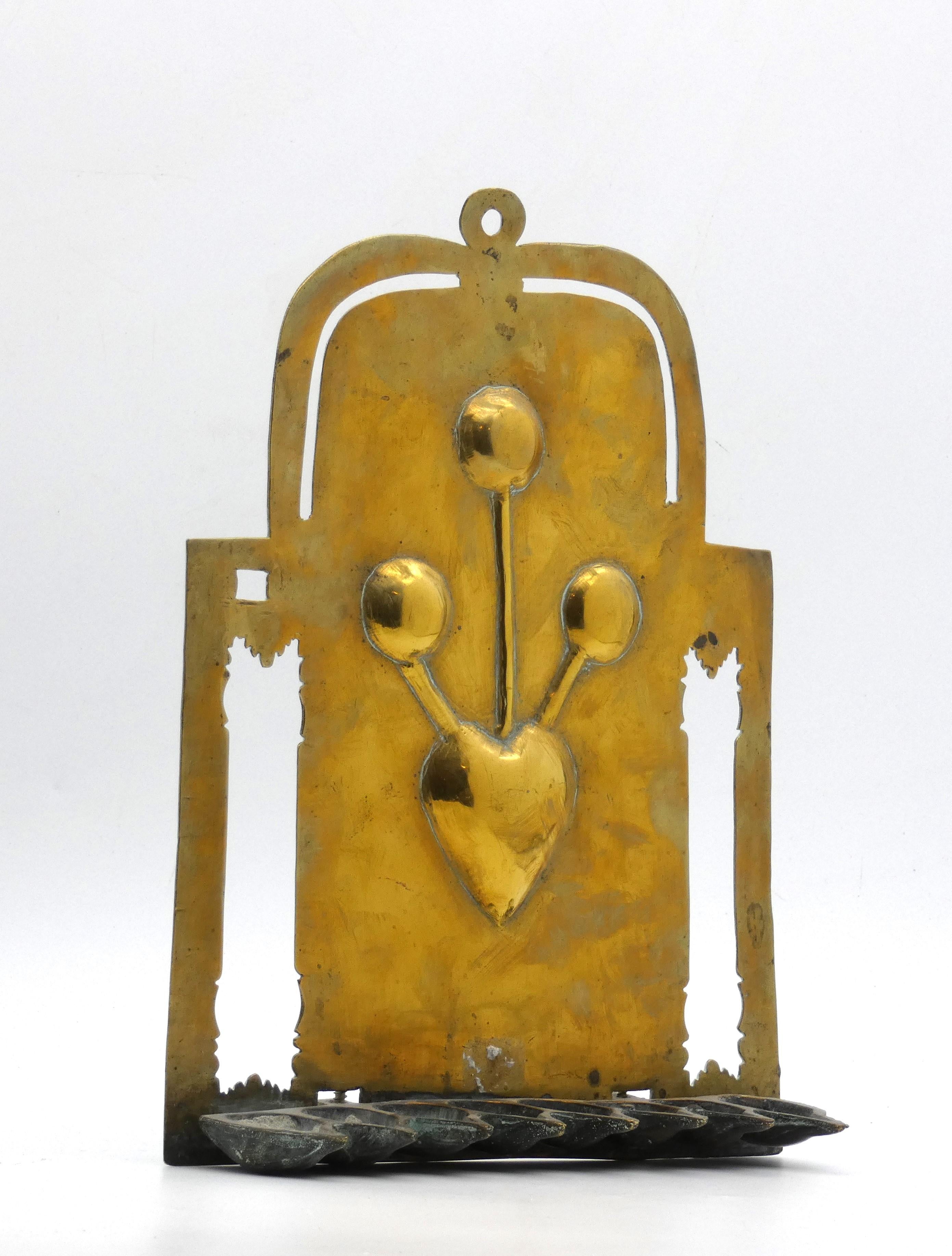 A Unique Brass Hanukkah Lamp from the Netherlands made in the  19th Century.

This uncommon Hanukkah lamp's lower square backplate is framed by its foliate piercings flanking the center heart-shaped design with flower bulbs seemingly sprouting from