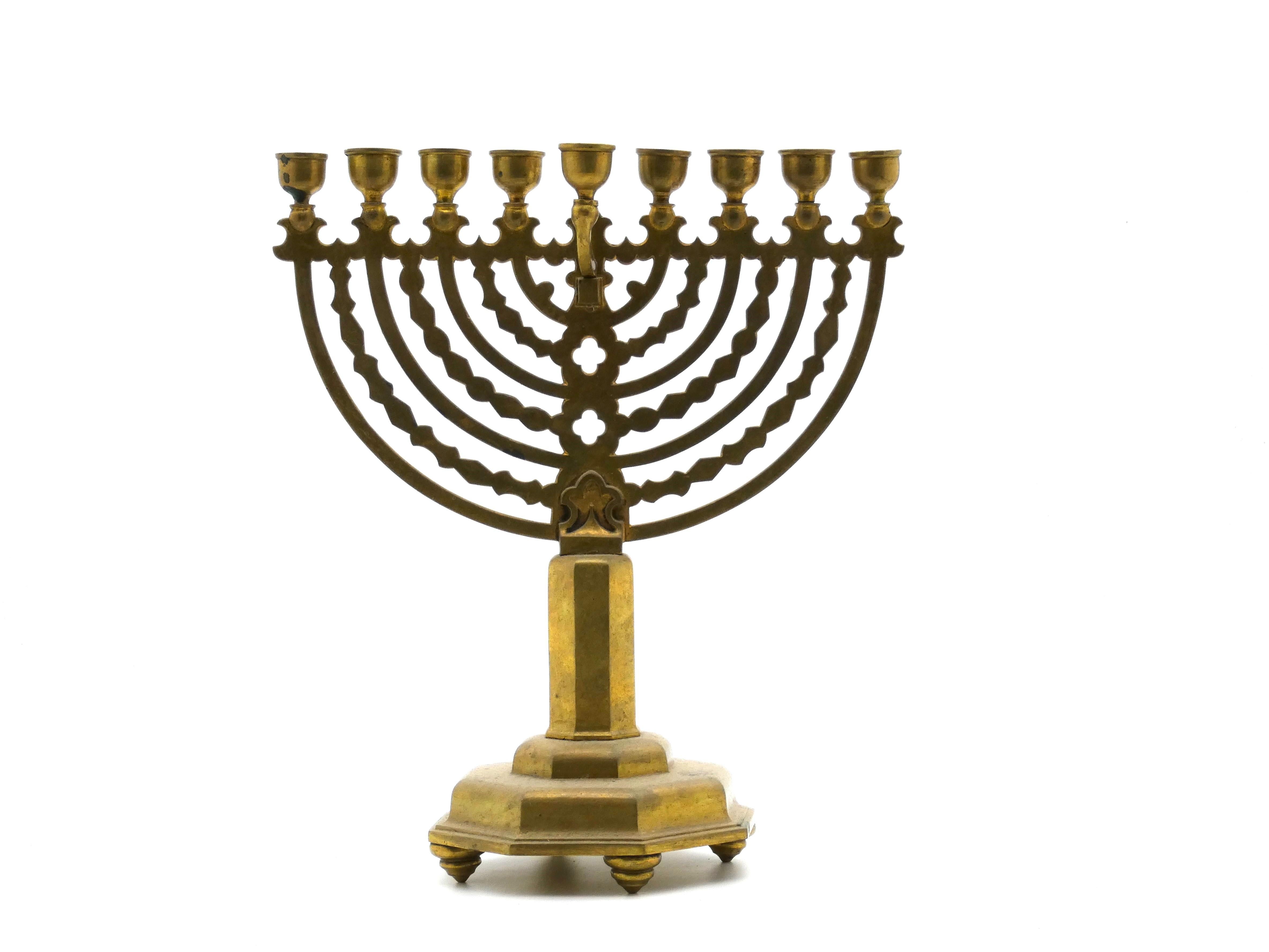 This German brass Menorah is indicative of the neo-gothic style of that period and suggests a date around the turn of the twentieth century.

Hanukkah menorah rests on an octagonal stepped base supported by four flywheel-shaped legs. 

Base is
