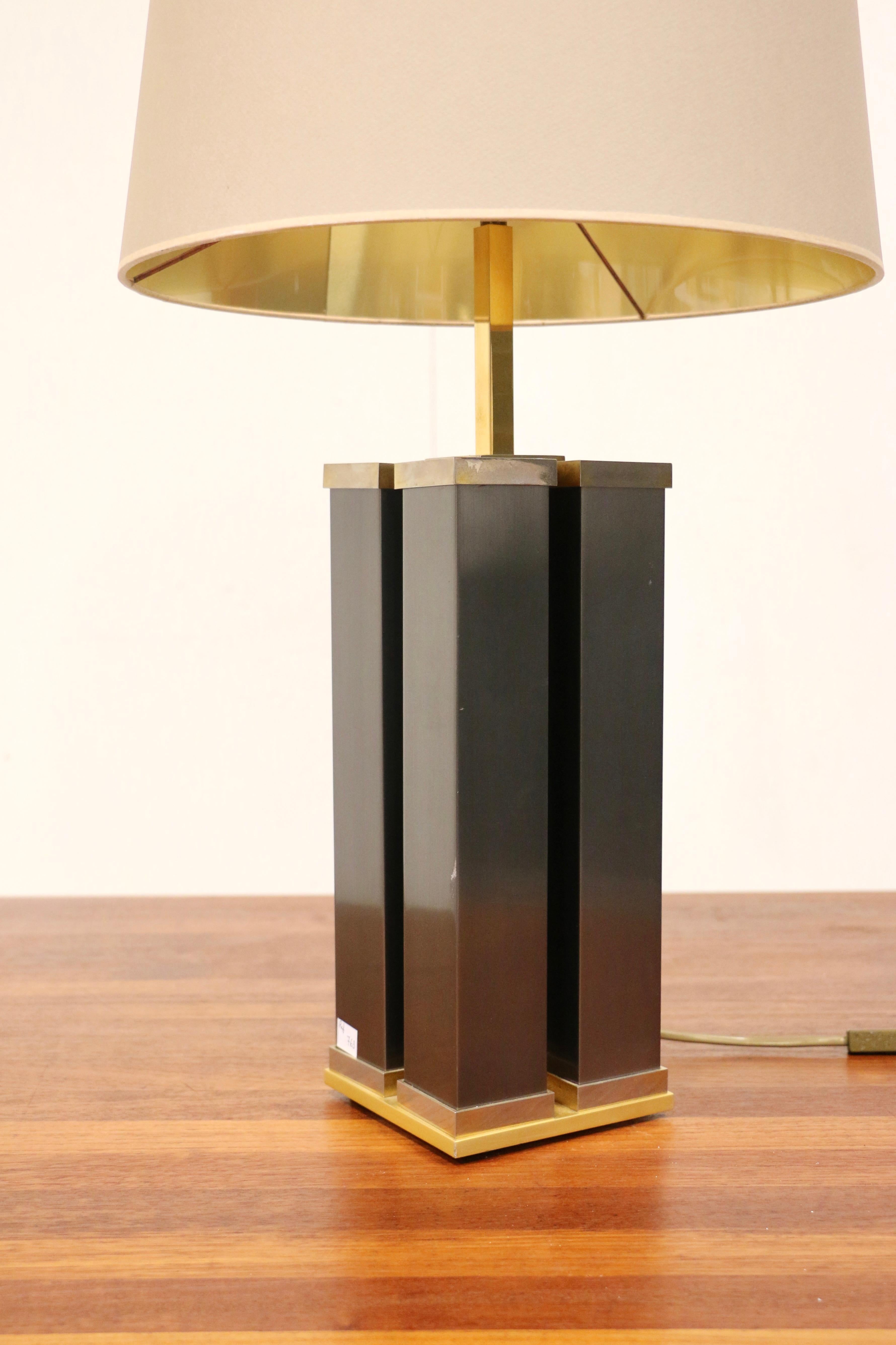 A large lamp with a square base in brass and brushed stainless steel.