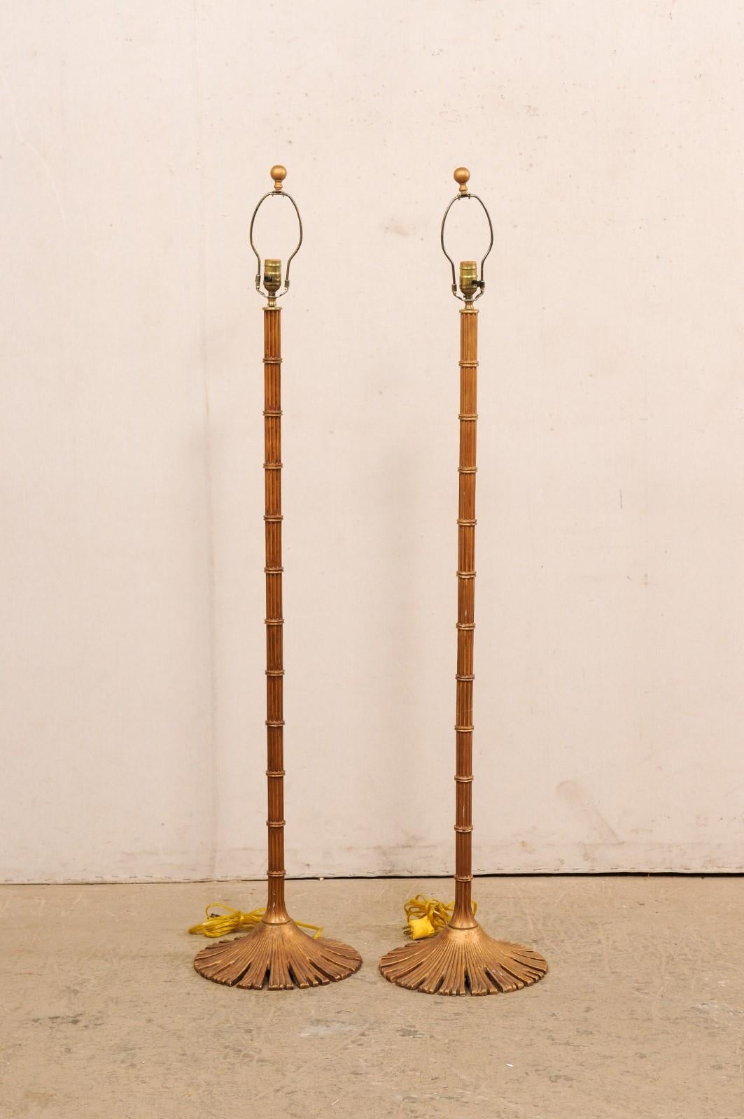 A pair of brass floor lamps from American company Chapman Manufacturing Company. This vintage pair of brass floor lamps have a beautifully reed-style bamboo designed column, with rounded base in a splayed out a lovely pattern reminiscent of a flower