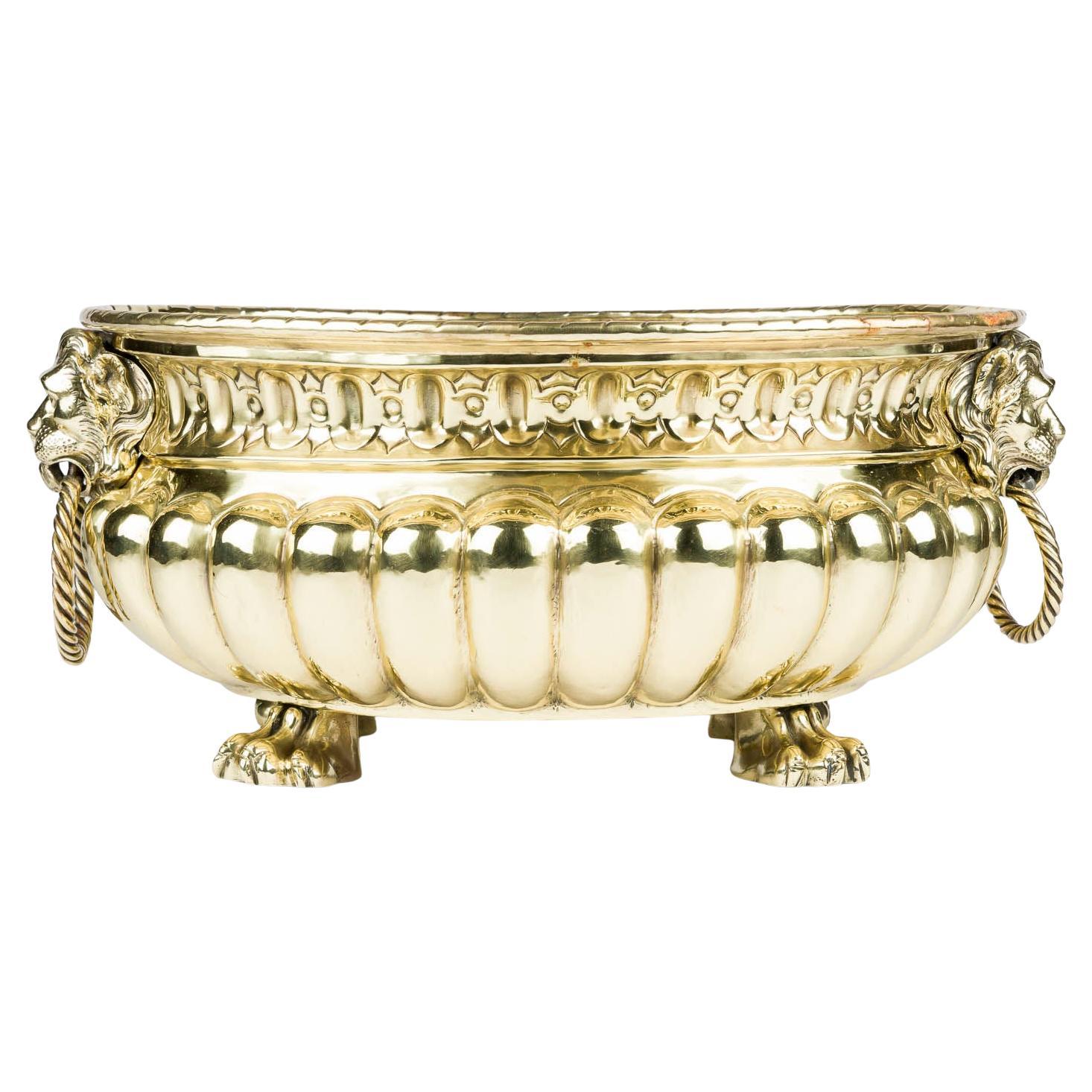 A brass repoussé jardinière with ring handles and paw feet