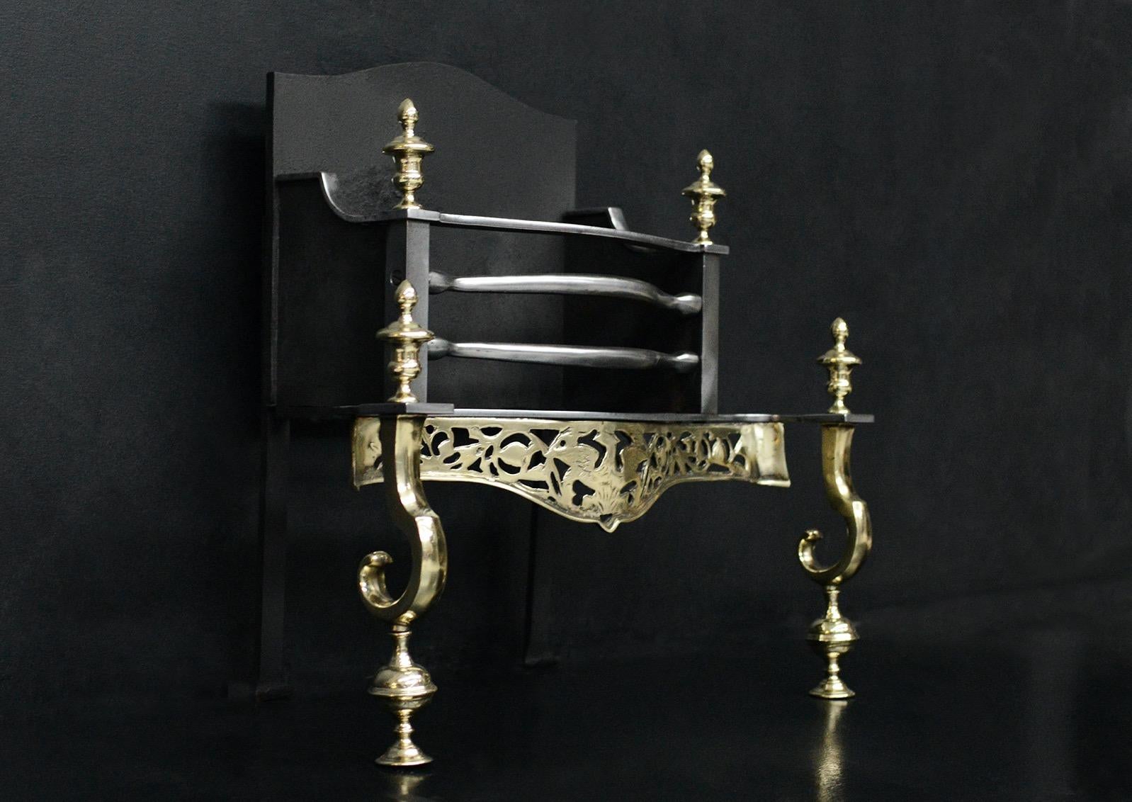 A brass and steel firegrate. The scrolled legs surmounted by urn finials, the decorative fret surmounted by serpentine steel front bars. Plain back behind. English, late 19th / early 20th century. 

Width At Front:	620 mm      	24 ⅜