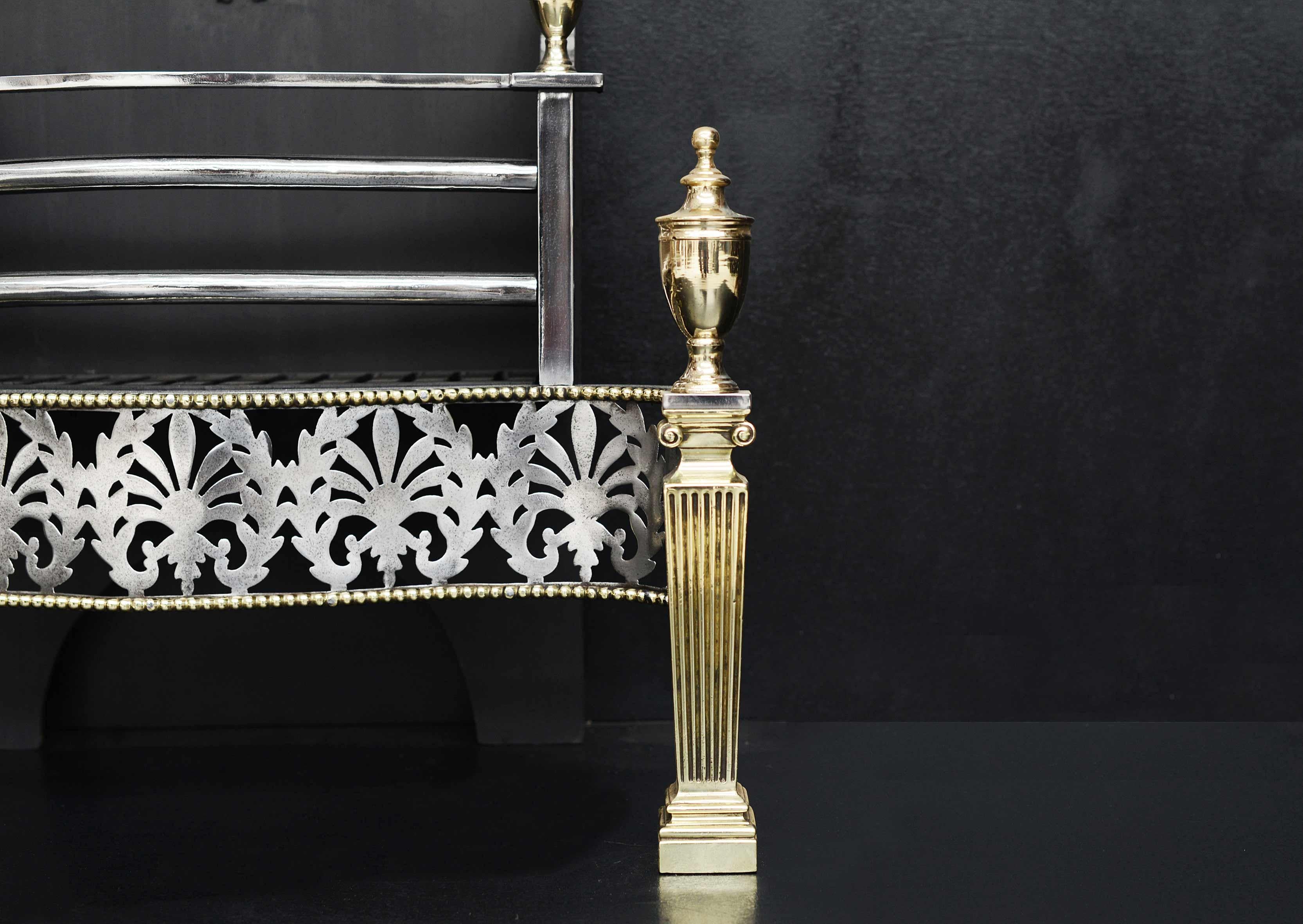 A brass and steel firebasket in the Georgian style. The tapering brass legs with ionic capitals, surmounted by urn finials. The pierced steel fret with Athenian motif with brass beading above and below. The burning area with polished steel front