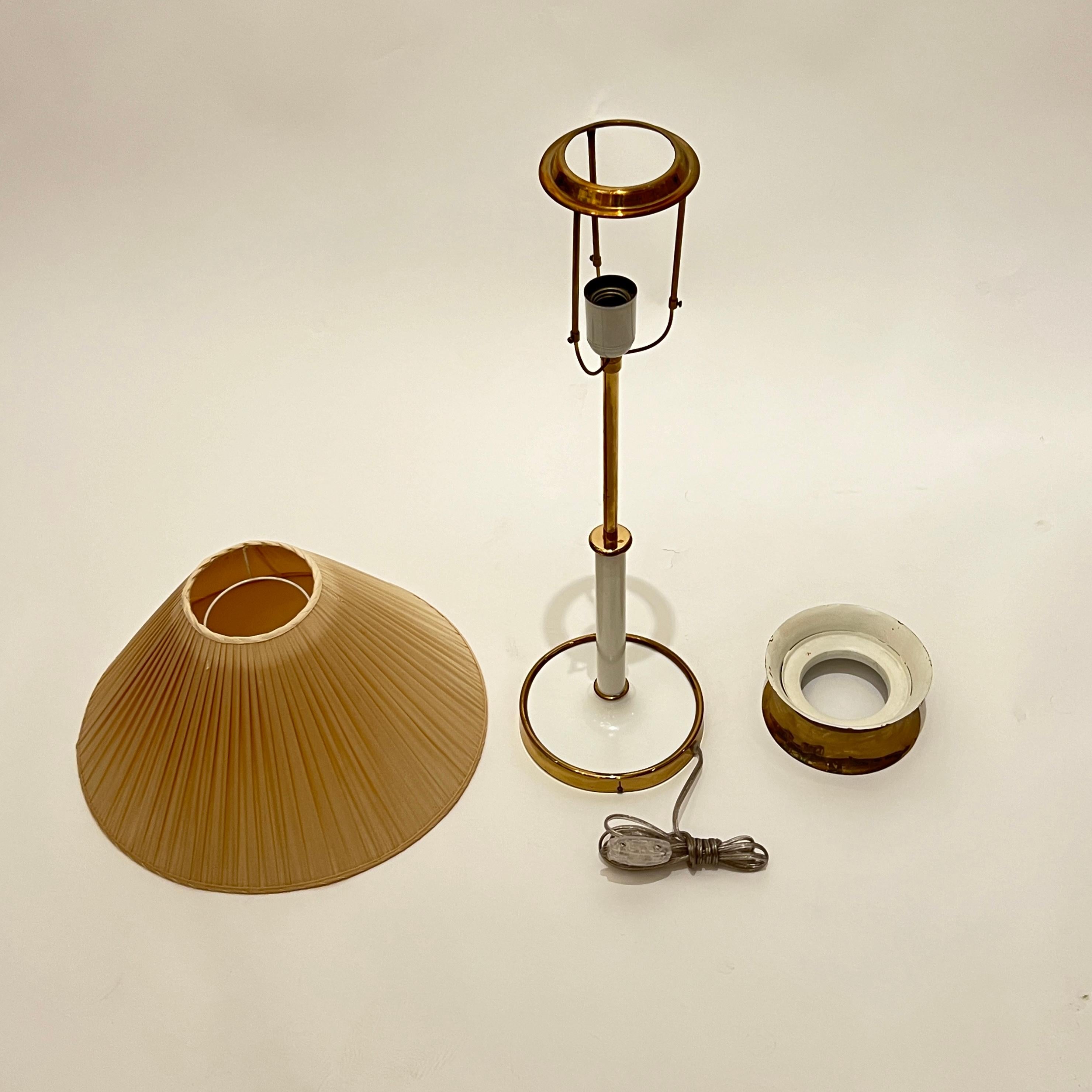 A Model 2466 table lamp designed by Josef Frank (1885-1967) for Svenskt Tenn. The brass base and stem in white lacquer, with the original pleated fabric shade topped with a brass cap that diffuses the light upward.
