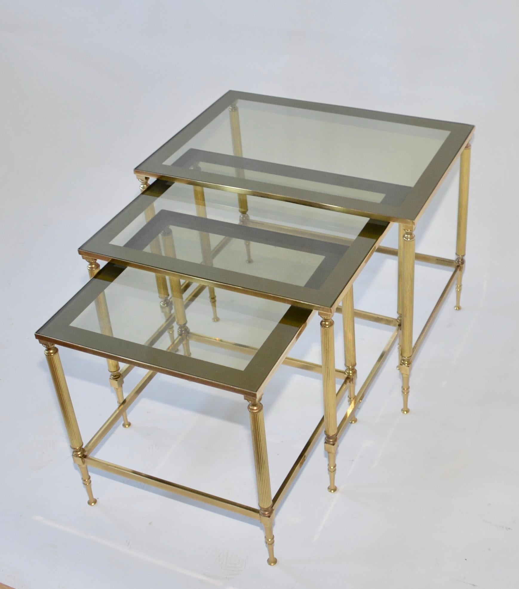 Vintage nest of three tables. The frames are in brass and each table has a smoked glass top. Very elegant and in true Hollywood Regency style. The dimensions listed are for the largest table, The medium table is 40cm H, 45 W, 37 D, the small table