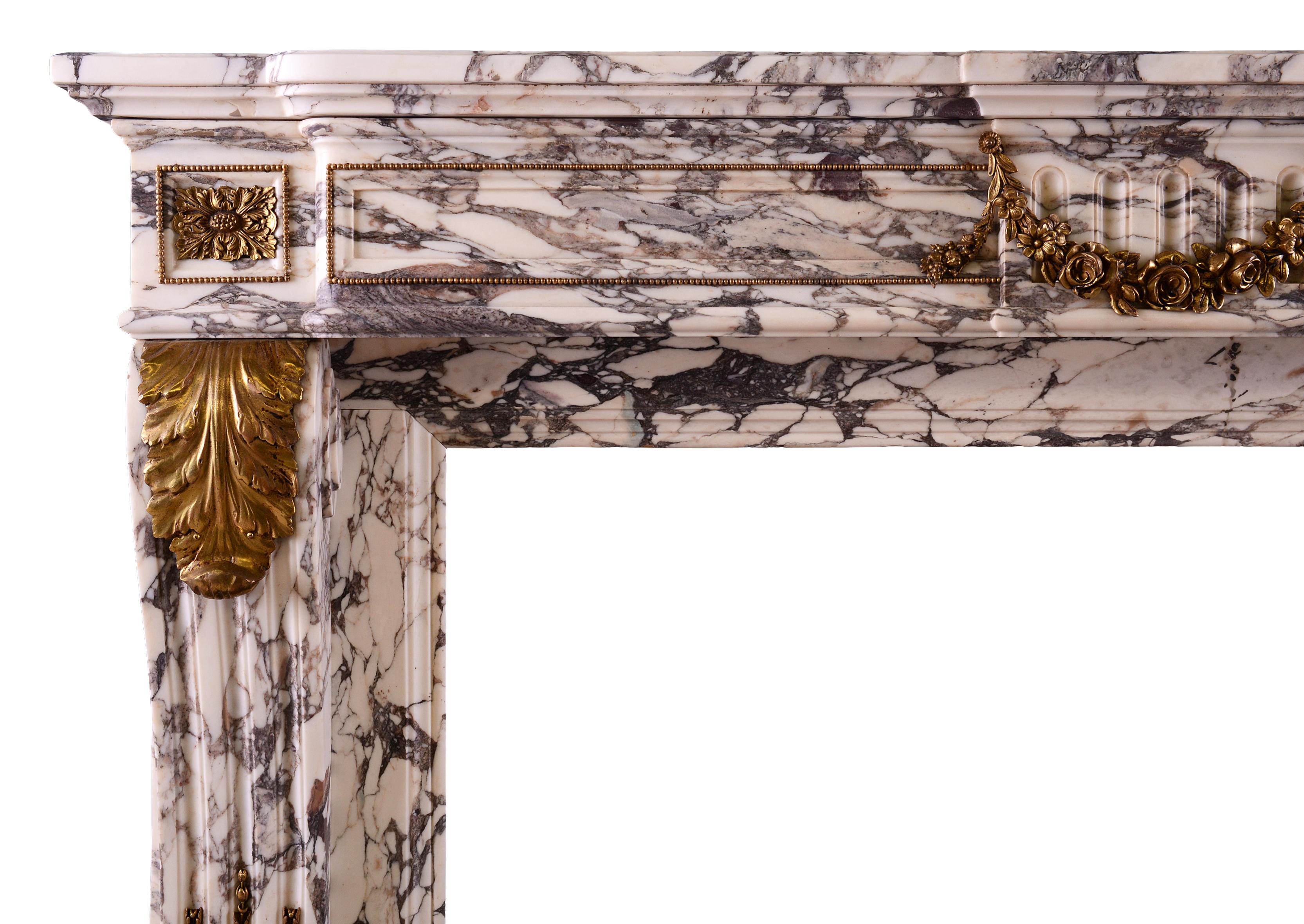 A good quality French Louis XVI style fireplace in Breche Violette marble. The scrolled, stop-fluted jambs adorned with acanthus leaf Ormolu, surmounted by rectangular ormolu paterae and beading. The panelled, shaped frieze with Ormolu beading