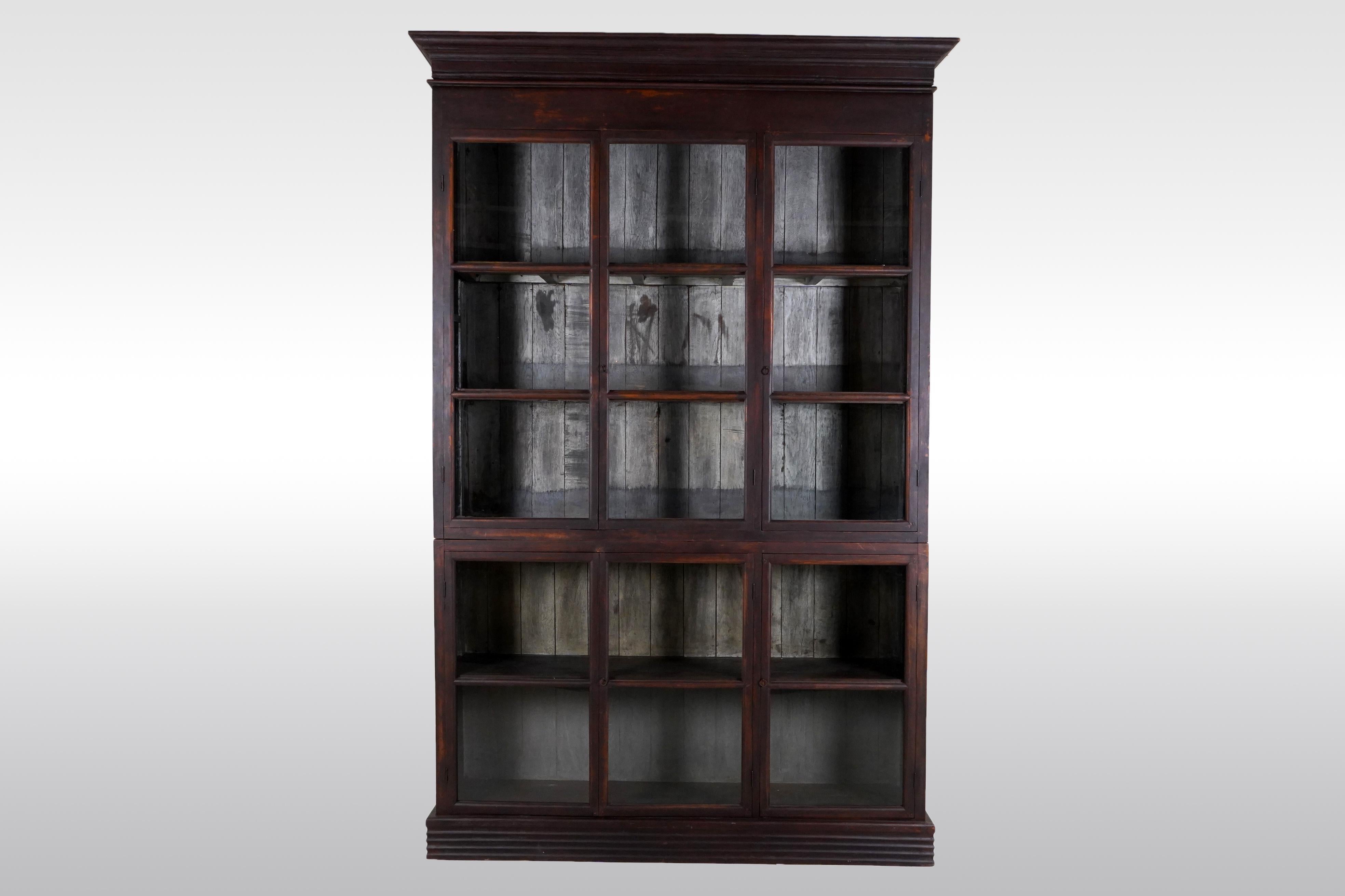 This monumental antique book cabinet was made from solid teak wood and dates to the early 1900's. During the time of the British Empire in India and Burma, much furniture was made in the Anglo-Indian style using native hardwoods and native