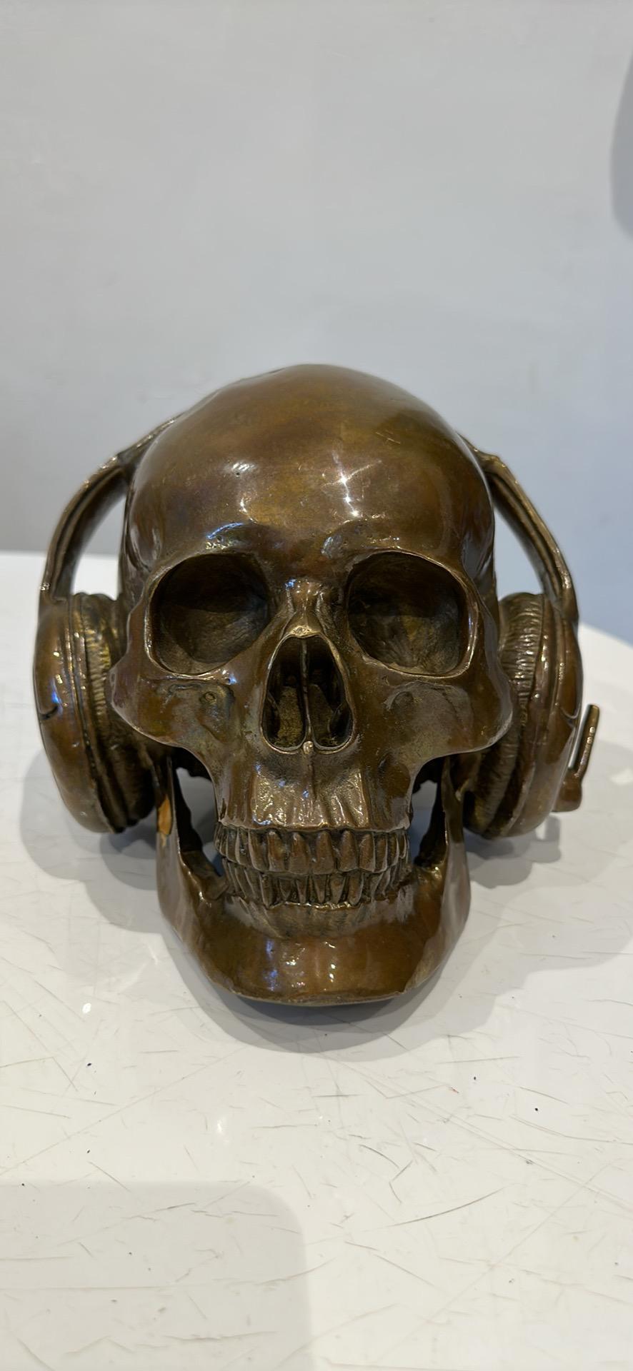 A contemporary bronze skull wearing headphones, in the style of Damien Hurst . Cast in bronze with a fantastic pitino. 