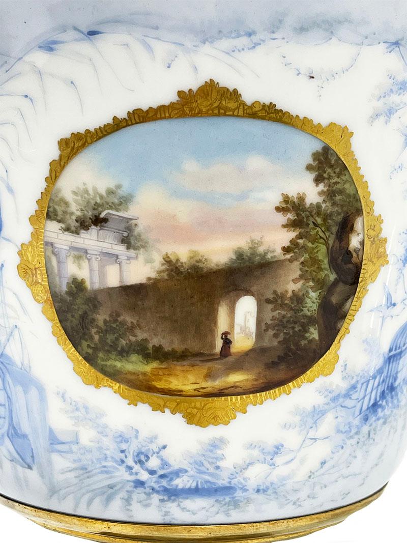 A bronze and porcelain jardiniere

A bronze porcelain jardiniere with the foot made of broze and the bowl of porcelain with at the front a scene in light blue with trees, birds and in a medallion painted a landscape with a woman walking out of an