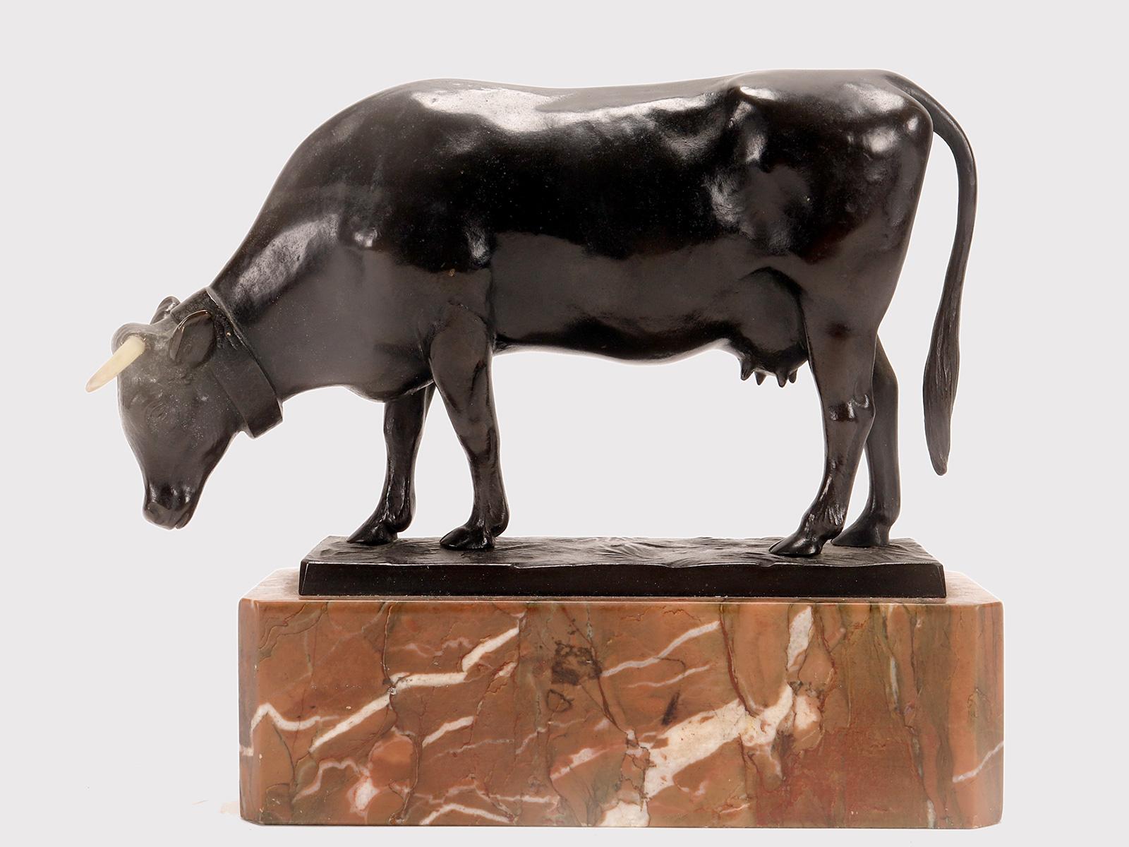 A lost wax bronze sculpture depicting a cow grazing on a meadow, on a Verona red marble base. The cow's horns are made of bovine horn. Signed Moseritz. France circa 1880.