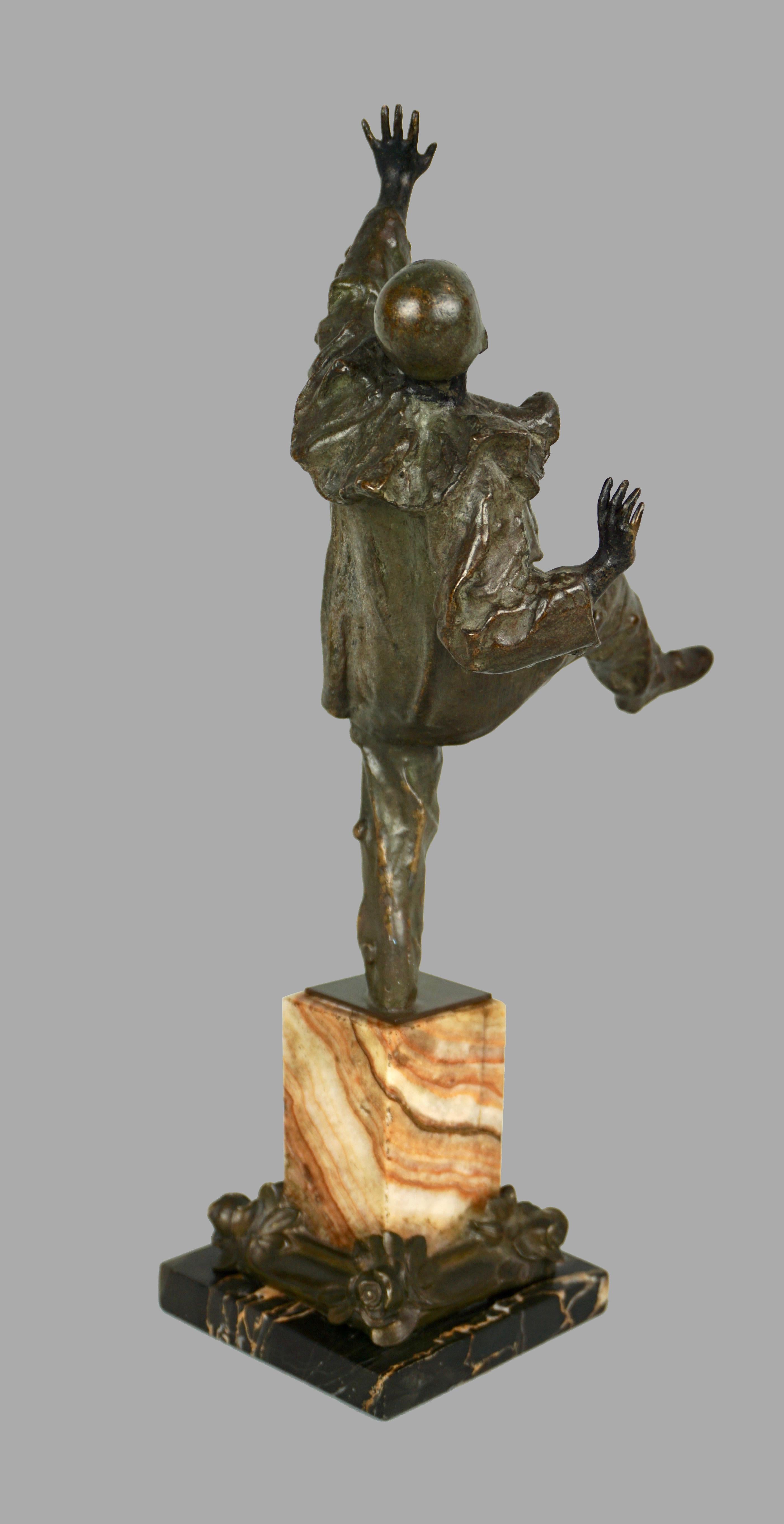 A charming and dynamic well-modeled bronze figure of a dancing harlequin or clown standing with one leg and arm in the air, fingers outstretched, dressed in a flowing garment and wearing a skull cap. Mounted on a 2 color marble base. Circa 1900.