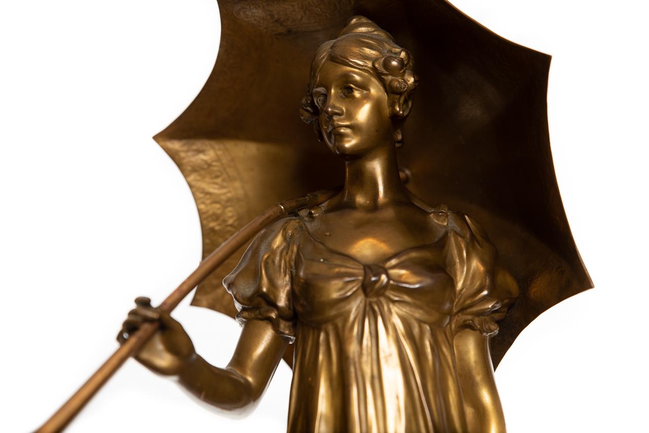 A bronze figure of a beautiful round woman dressed in high-waisted evening dress holding an umbrella aloft. By Austrian sculpture Hans Müller (1873–1937).
Figures stands atop a Siena style marble base.
Unusual to find this high quality bronze