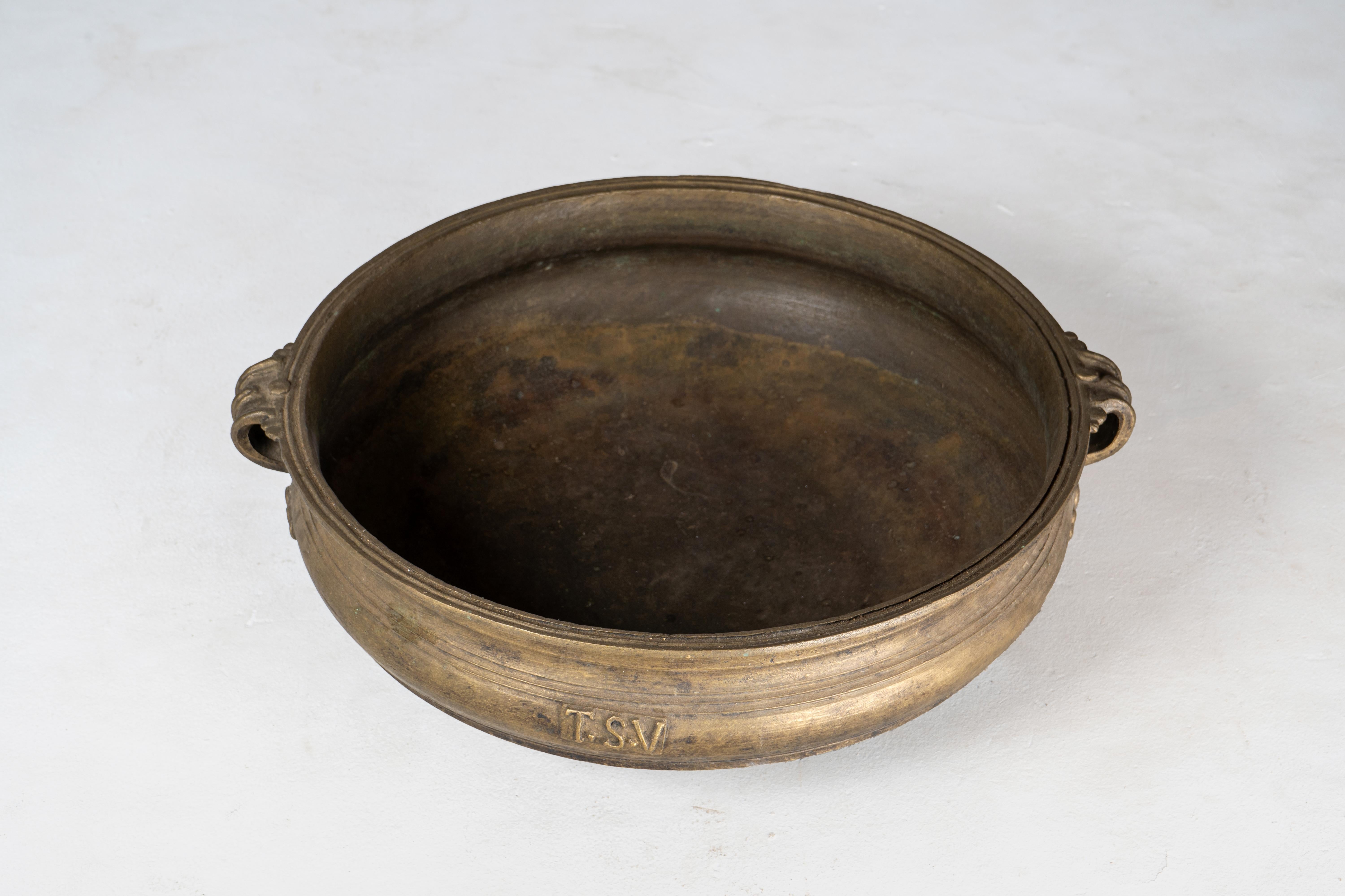 This shallow bronze bowl is an open fire cooking vessel known as urli, used throughout southern India for preparing ayurvedic medicines and cooking large quantities of food for gatherings and ritual offerings. Cast of bell bronze using the lost wax