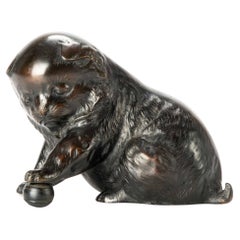 A bronze okimono depicting a study of a puppy playing with a ball