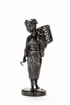 A bronze okimono depicting a walking peasant woman