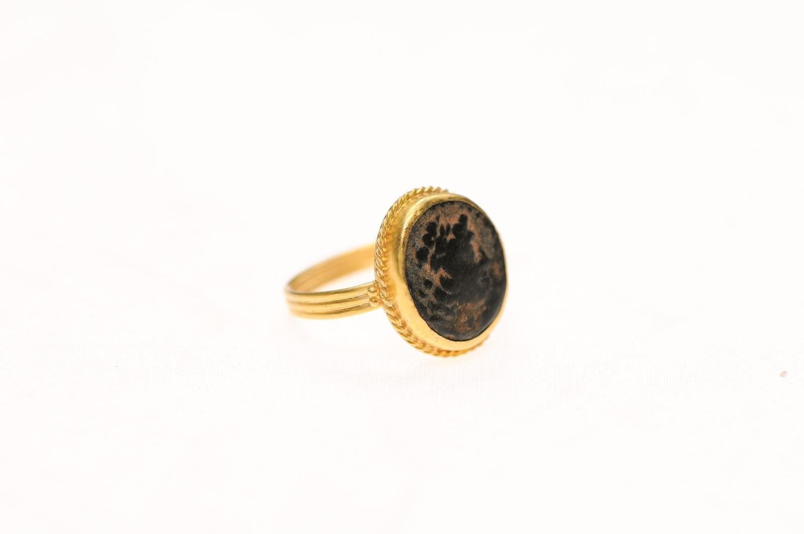 A bronze coin from the Ancient Roman Empire fashioned into an attractive ring trimmed with 21K gold accents. There is a marvelous patina that demonstrates the coin's age. This is dated approximately from the 1st to 3rd Century AD and was created by