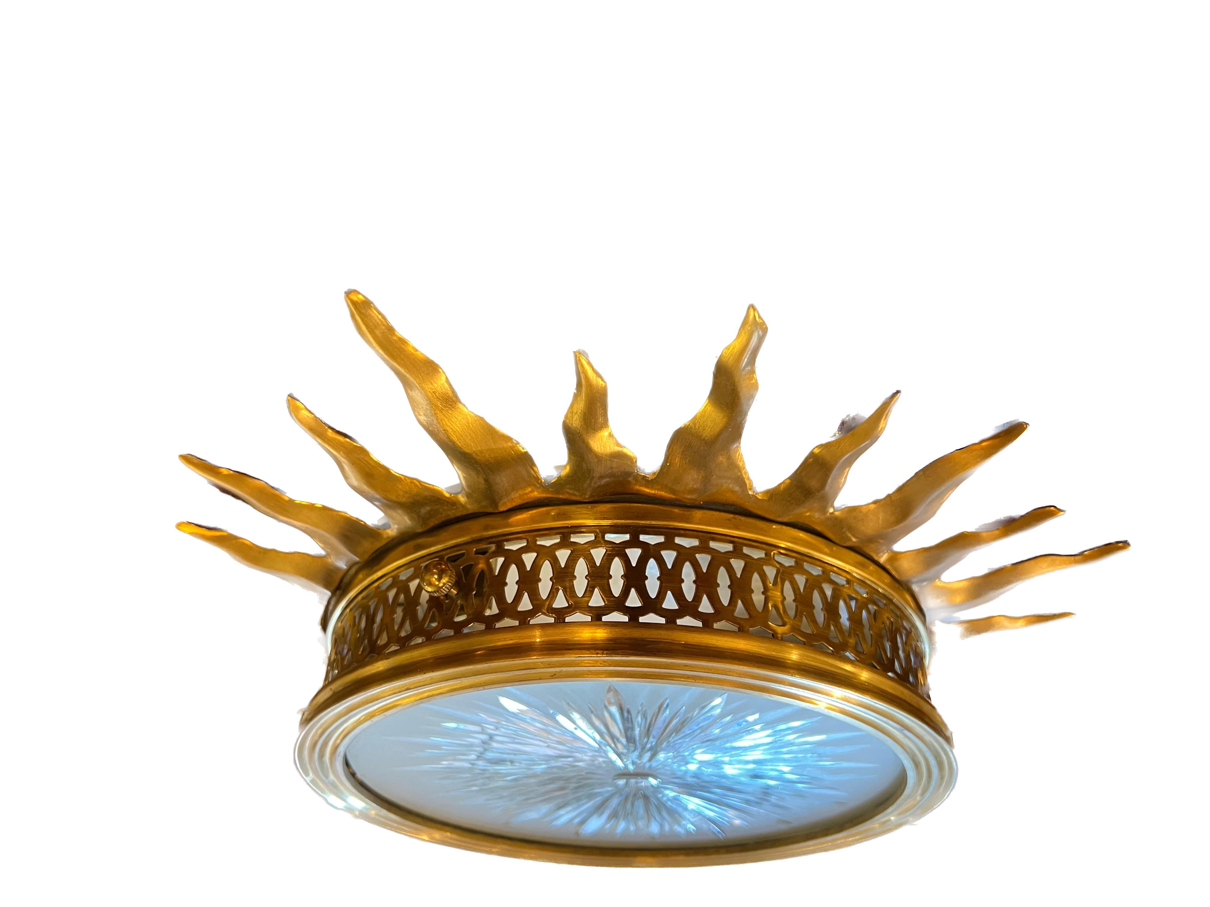 A rare set of four bronze sunburst design flush mounts. The hand carved glass with a  sunburst pattern frosted on the underside, concealing two candelabra sockets, maximum wattage 150. Four available.