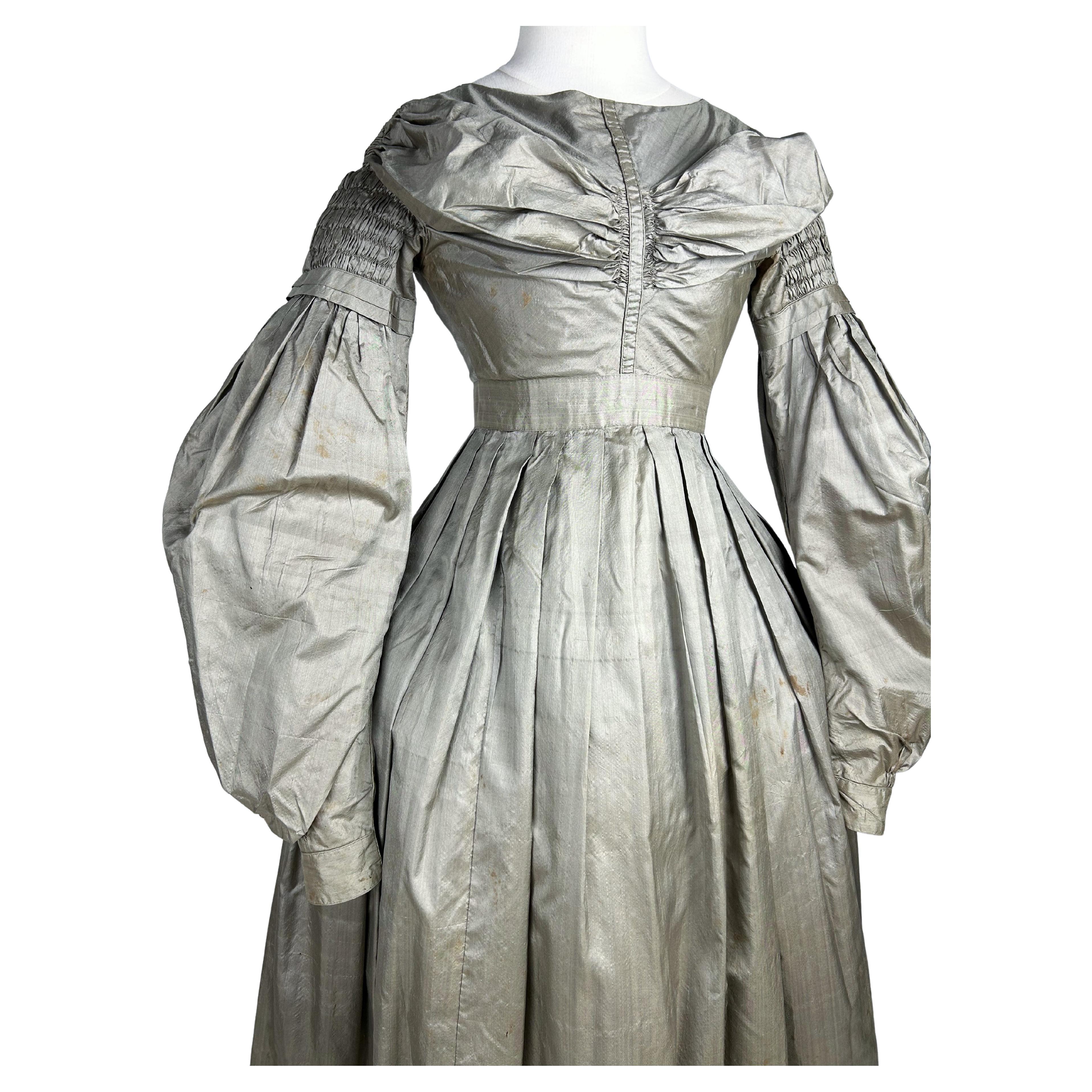 Circa 1840
France

Bronze or puce taffeta day dress dating from the end of the reign of Louis-Philippe. Brown chintz-lined dress with high-waisted bodice, draped pleats highlighting the bosom and closed by hooks in the back with a V-cut. Small oval