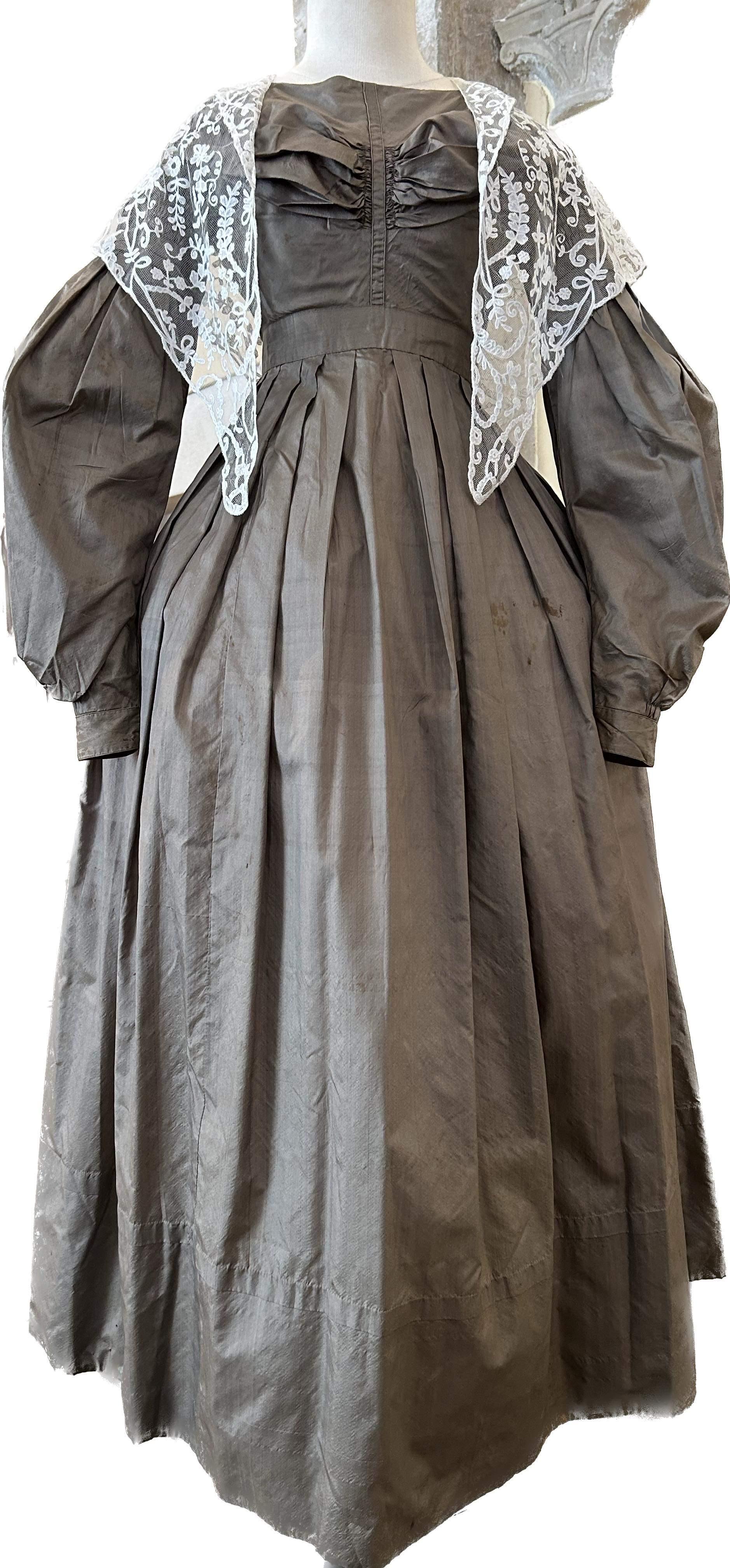 Circa 1840
Francia

Abito da giorno in taffettà color bronzo o viola risalente alla fine del regno di Louis Philippe. Abito marrone foderato in chintz con corpetto a vita alta, pieghe drappeggiate che evidenziano il seno e chiuso da ganci sul retro