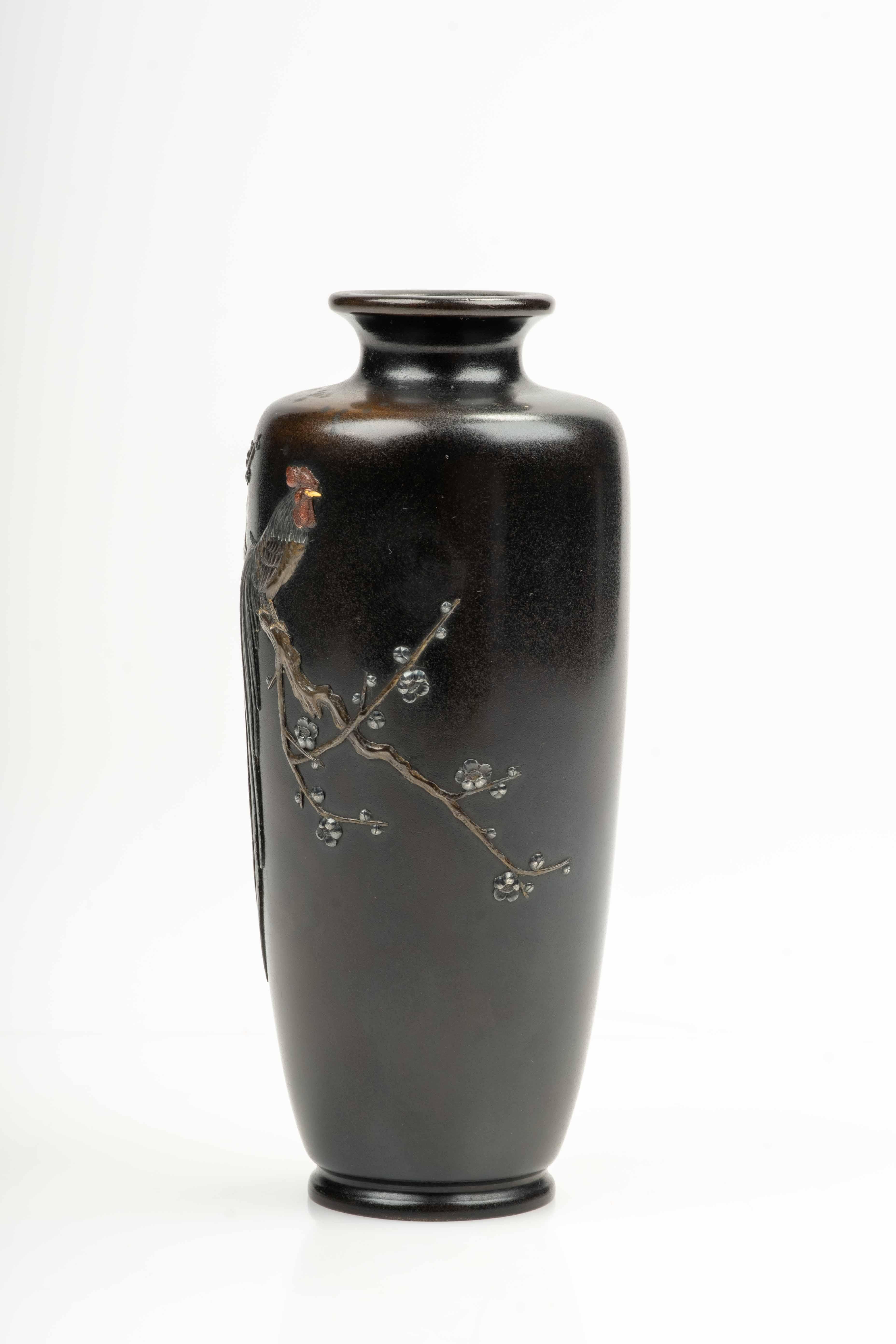 Jarrón de bronce con incrustaciones metálicas mixtas de plata, bronce dorado y bronce patinado, que presenta en el centro un gallo onagadori posado sobre una rama de ciruelo (ume) en flor. 

El jarrón lleva la firma de Toshiji en el lateral y una