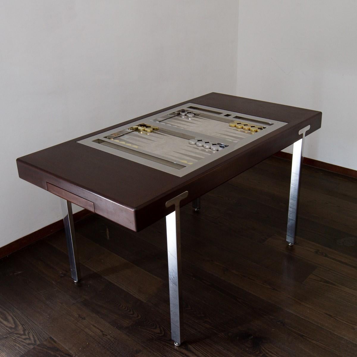 A matt brown polish and polished nickel backgammon table with a tilt top games table, complete with brass and chrome playing pieces. 

The pieces can be stored in the drawers which also act as the hold and release mechanism for the table top,