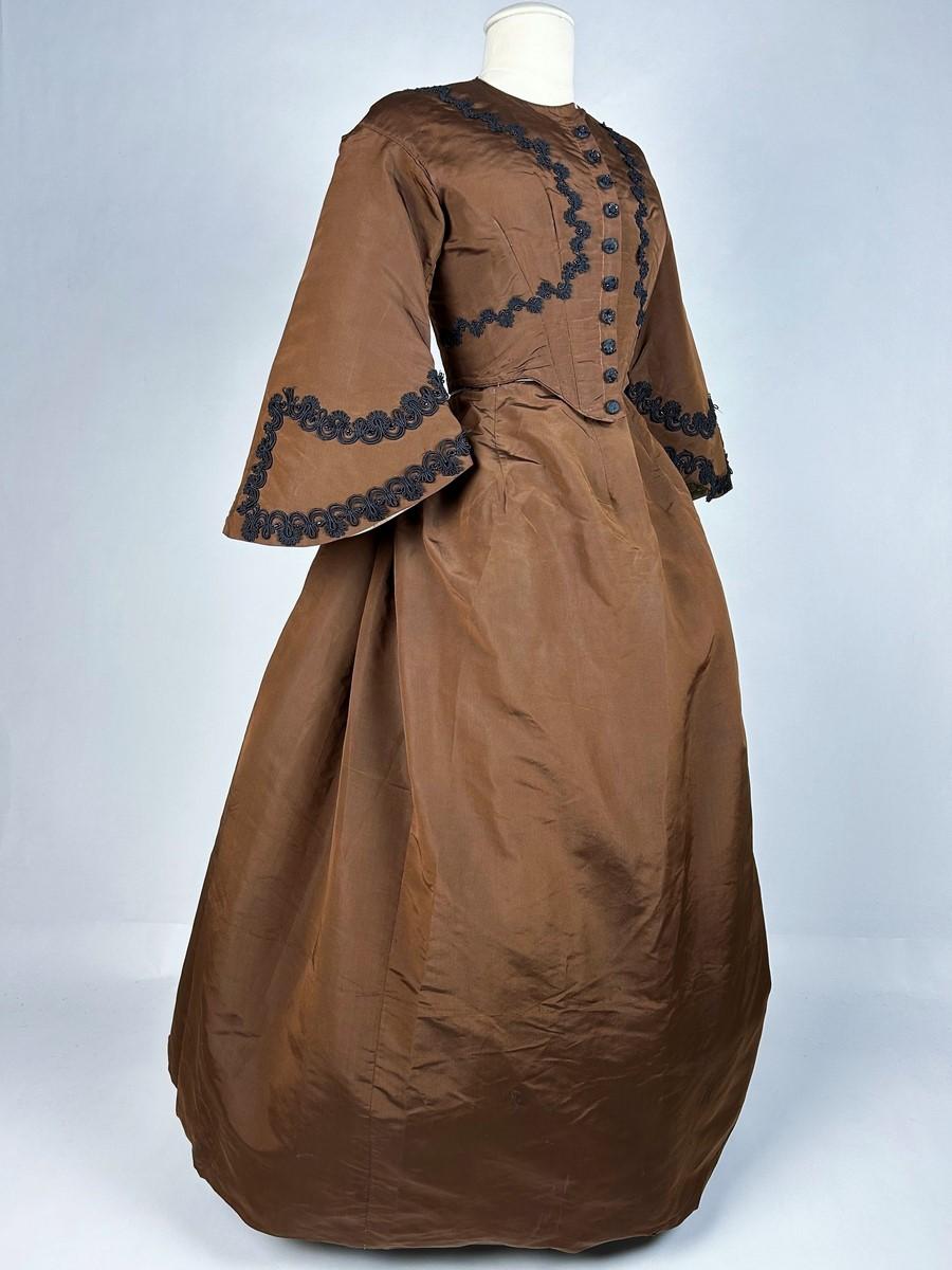 Circa 1880
France

A brown silk faille day dress, skirt and bodice dating from the early French Troisième République. Whalebone bodice, staple front choker and large pagoda sleeves. The bodice is complete with ten buttons (buttons are slightly