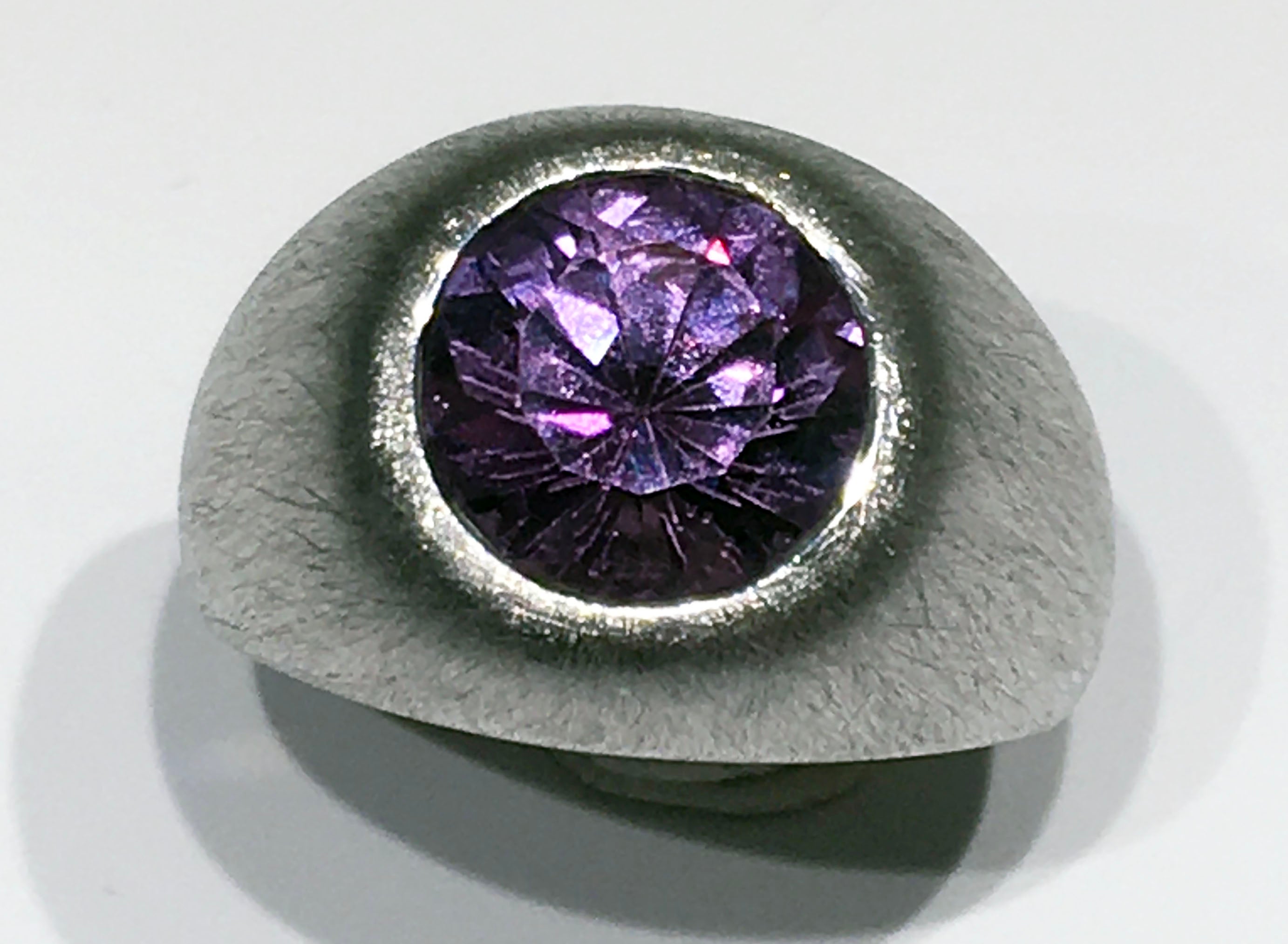 A Brushed Silver Ring with Cultured Color Change Sapphire. Cultured Color Change Round Brilliant Sapphire is 4.8 Carats, Silver weight is 8.5 Grams. Ring size is 7.5 USA

Originally from San Diego, California, Kary Adam lived in the “Gem Capital of