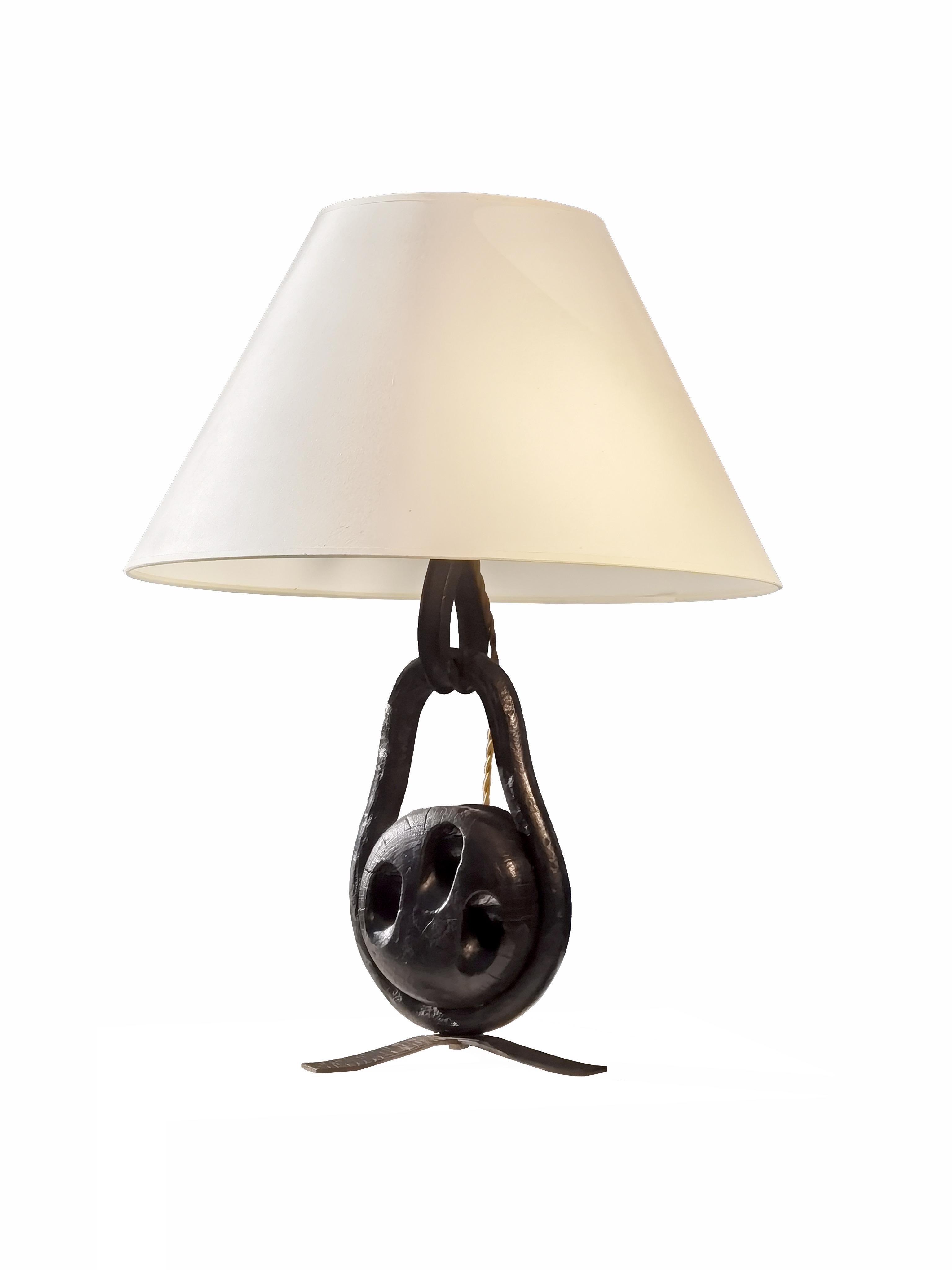 Eine starke und kräftige Tischlampe aus Schmiedeeisen mit einer patinierten massiven Holzrolle, hergestellt von einem französischen Handwerker in den 60er Jahren.
Die Leuchte basiert auf einem schmiedeeisernen Dreibein, das eine massive eiserne