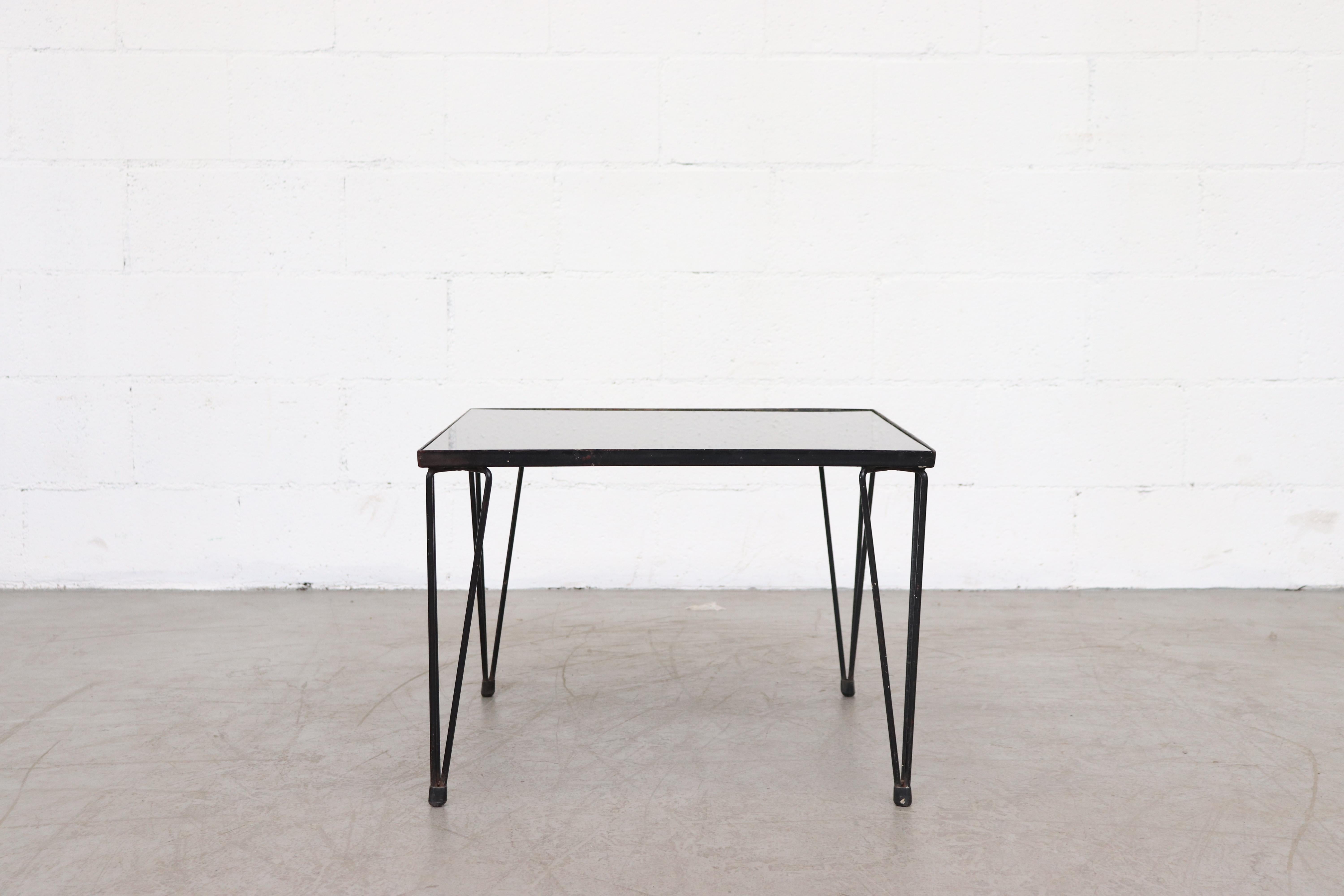 Mid-century, black glass coffee table with adorable enameled metal hairpin legs. The table brings to mind those created by Dutch designer Arnold Bueno de Mesquita for manufacturers Groos and Spur (both based in The Netherlands) during the 1950s and