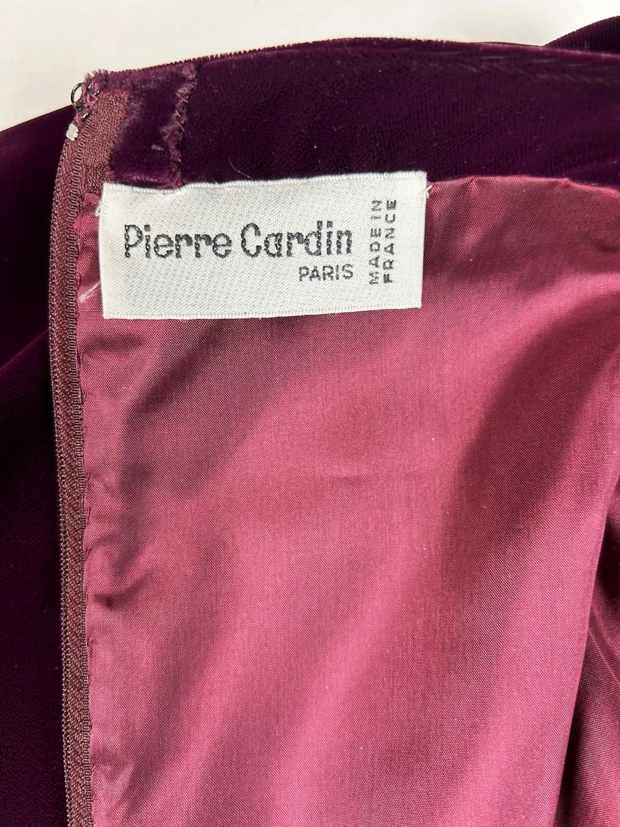 Circa 1980

France

A long evening dress in Burgundy velvet by Pierre Cardin Haute Couture dating from the 1980s. Sheath dress with boat neckline and long sleeves zipped at the cuffs. The bottom of the dress, slit on one side, is adorned with a
