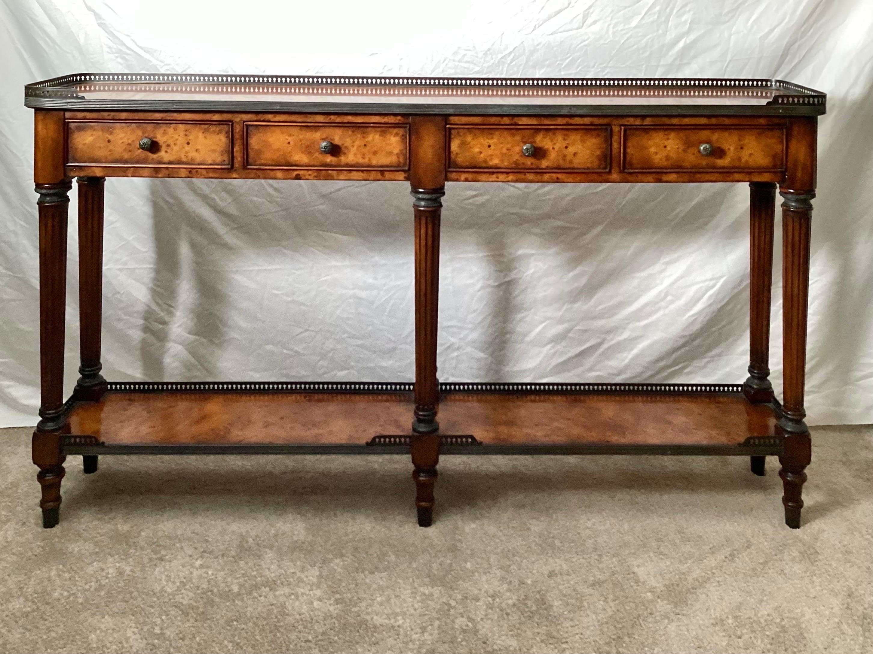 Elegant narrow burled walnut console table with aged brass gallery edge.  Four drawers with six fluted legs joined by a lower galley edge shelf.  33 inches high, 58 inches wide, and a slim 11 inches deep.  Marked on the inside of the drawer Maitland