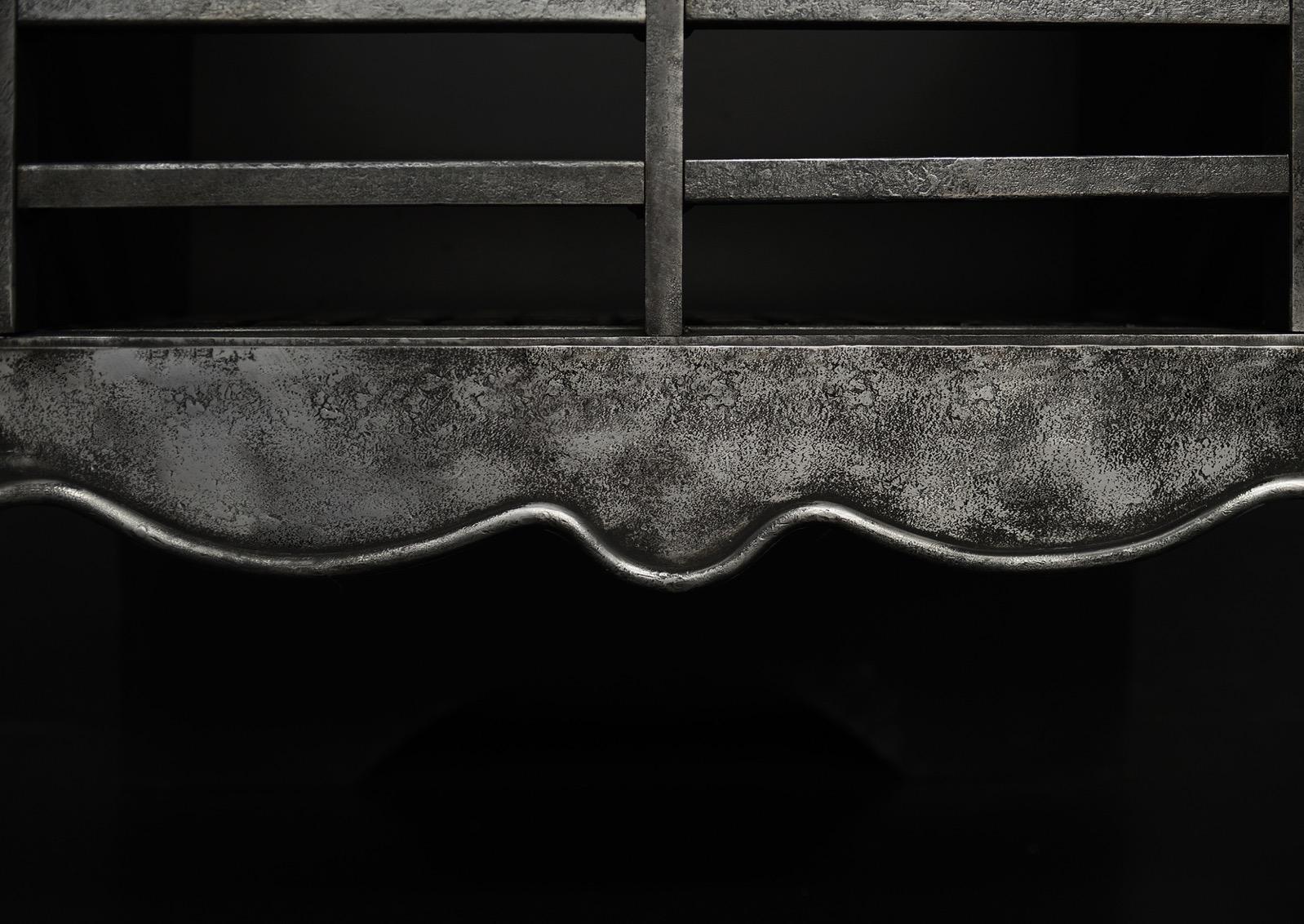 A burnished steel firegrate in the Georgian manner. The legs with quadruple columns surmounted by upright and ball finial. The shaped fret with plain front bars above. English, reproduction. Also available in burnished finish (Stock No.