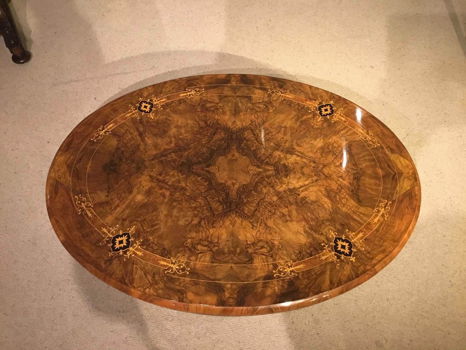 A burr walnut marquetry inlaid Victorian Period oval coffee table. Having an oval top veneered in beautifully figured burr walnut with an arabesque boxwood inlaid border with amboyna and ebony panels and having a burr walnut veneered frieze with a