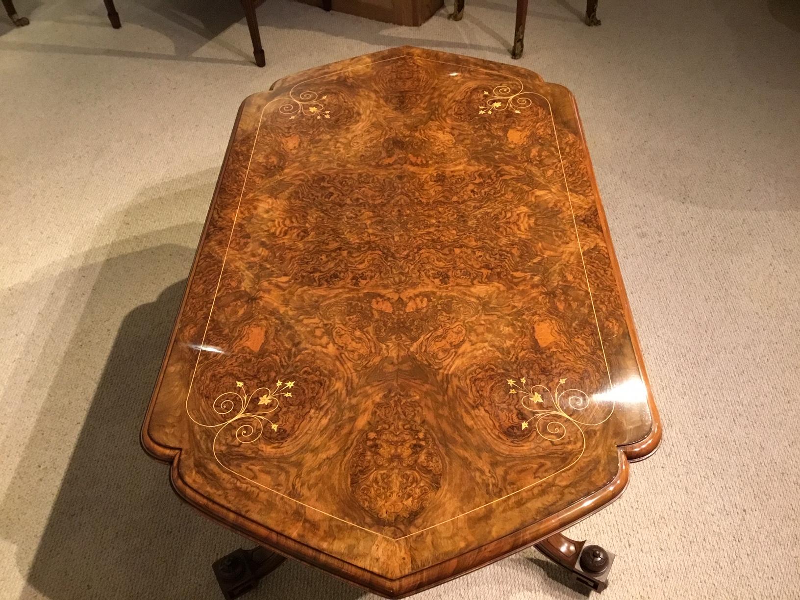 A burr walnut Victorian Period antique coffee table. Having an unusual shaped top veneered in beautifully figured burr walnut with fine quality marquetry line inlaid detail. Supported on four turned column supports, swept feet with Greek Key carving