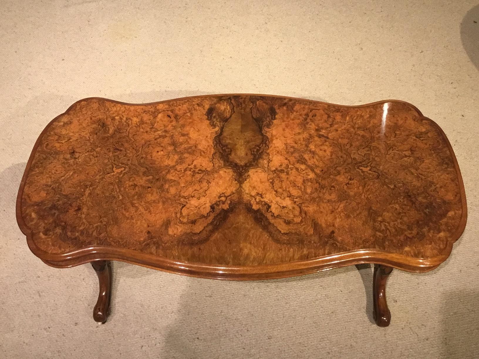 A superb burr walnut Victorian period coffee table. Having a serpentine shaped top veneered in the finest burr walnut . With a burr walnut veneered frieze and supported on turned and carved column supports with floral carved cabriole feet and brass
