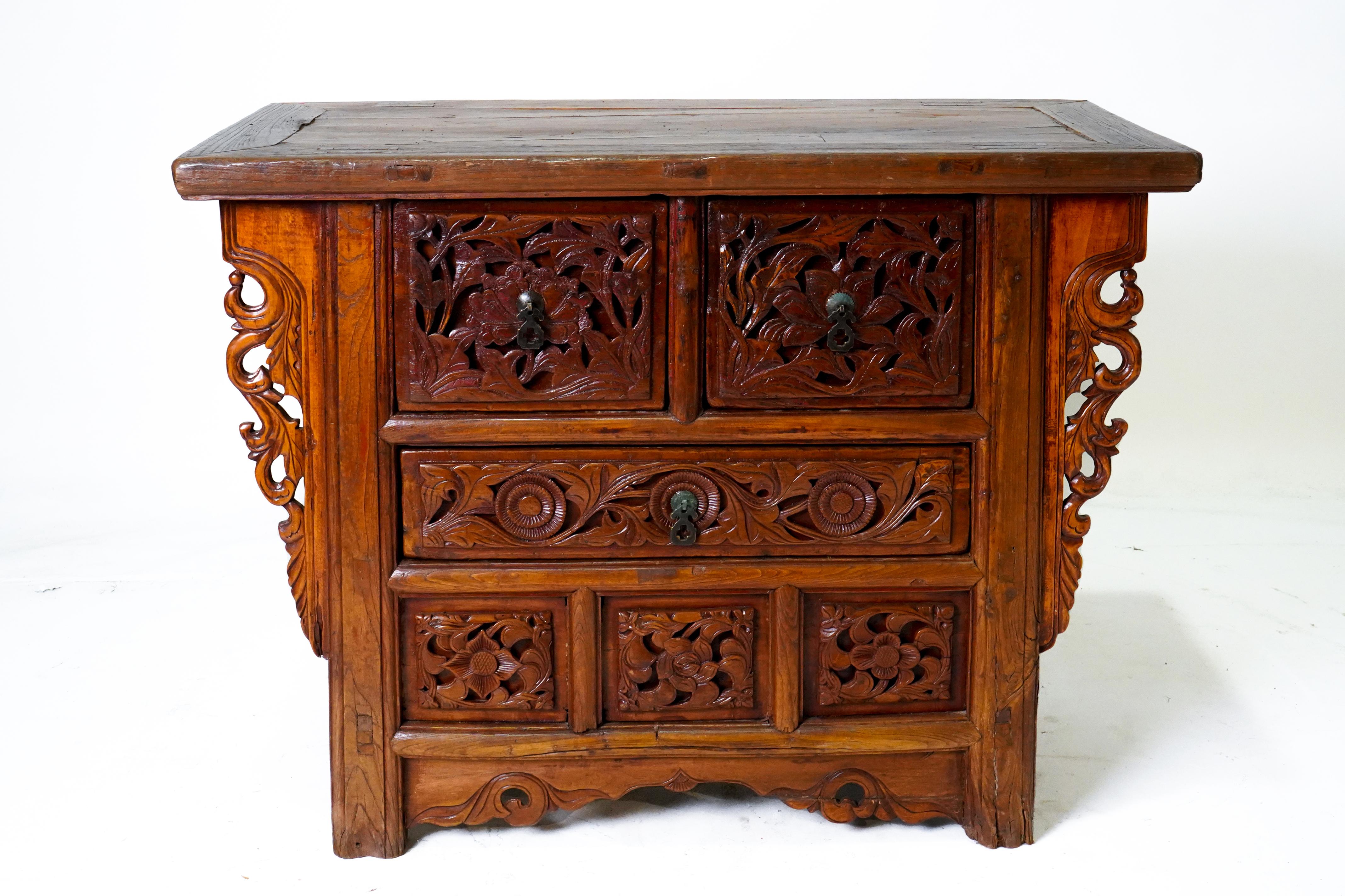 A Chinese Provincial-style wooden butterfly cabinet from the 19th century, with carved spandrels, drawers, doors and faded oxblood patina. This sturdy and expressive coffer, called a butterfly cabinet, features a rectangular floating panel top
