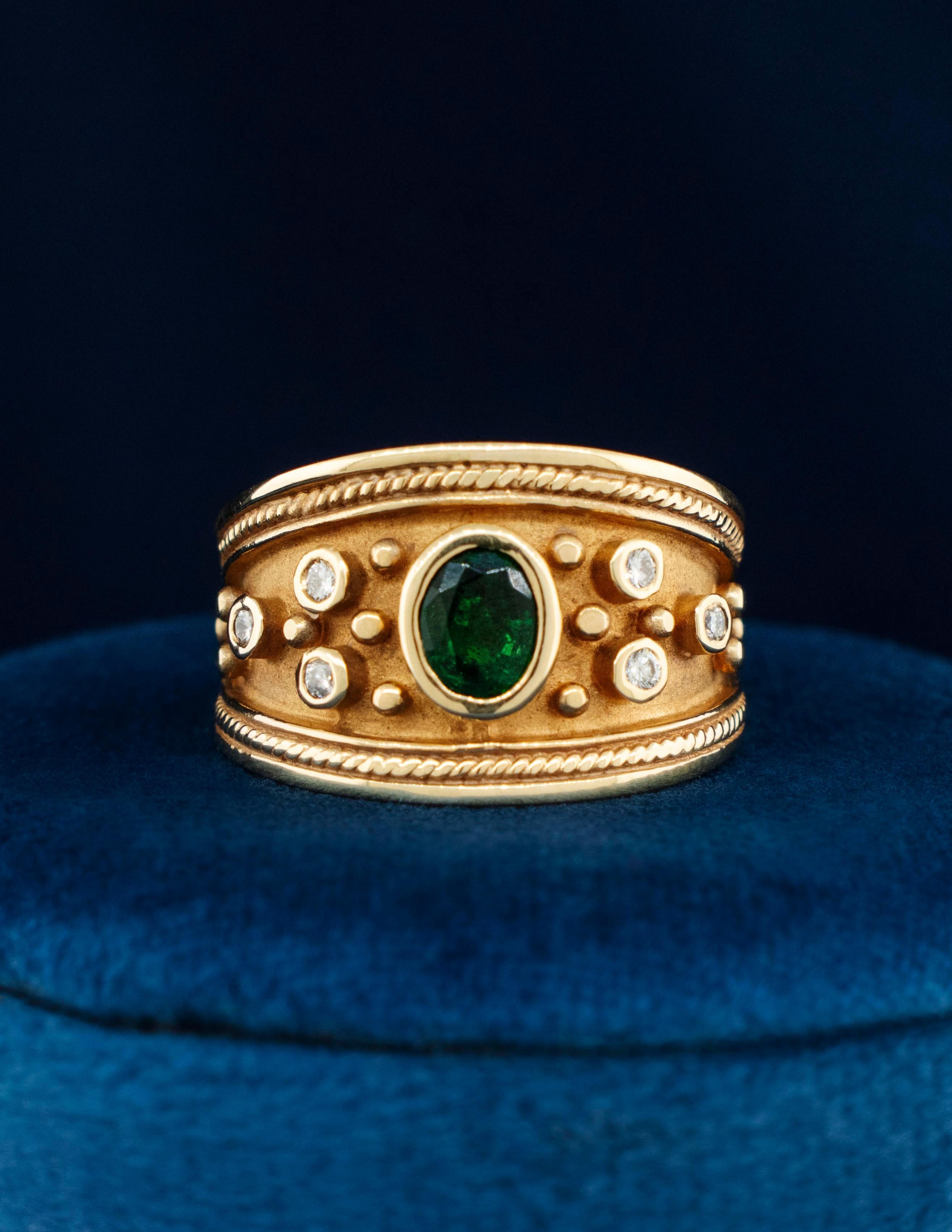 A 14K Yellow Gold Byzantine Ring with a bezel set deep green Natural Emerald weighing approximately 1/2 carat. There are six round brilliant diamonds flanking the Emerald center stone. The Byzantine style exhibits ancient techniques of beading,
