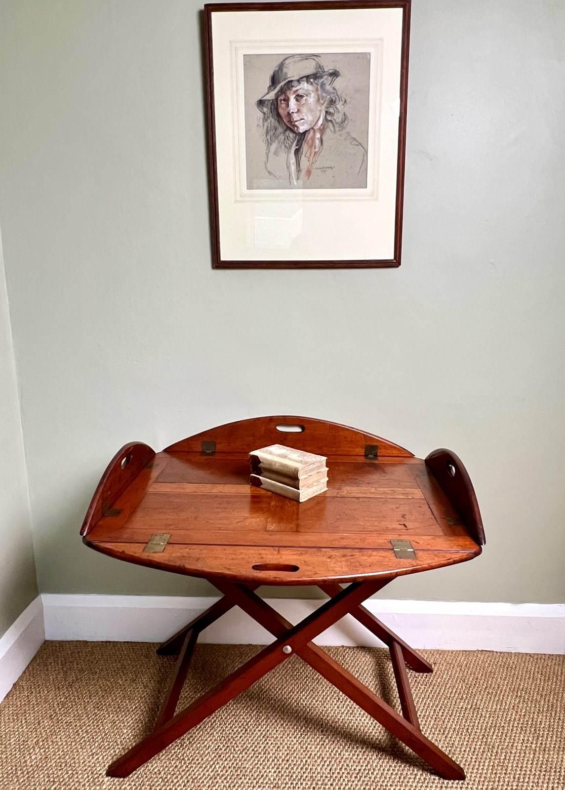 A very good example of a Campaign Butlers Tray Table from the late 19th Century. Crafted in a lovely rich mahogany which now has a lovely time worn patina. Having its original brass snap-hinges and stand with canvas webbing. Stamped to tray and