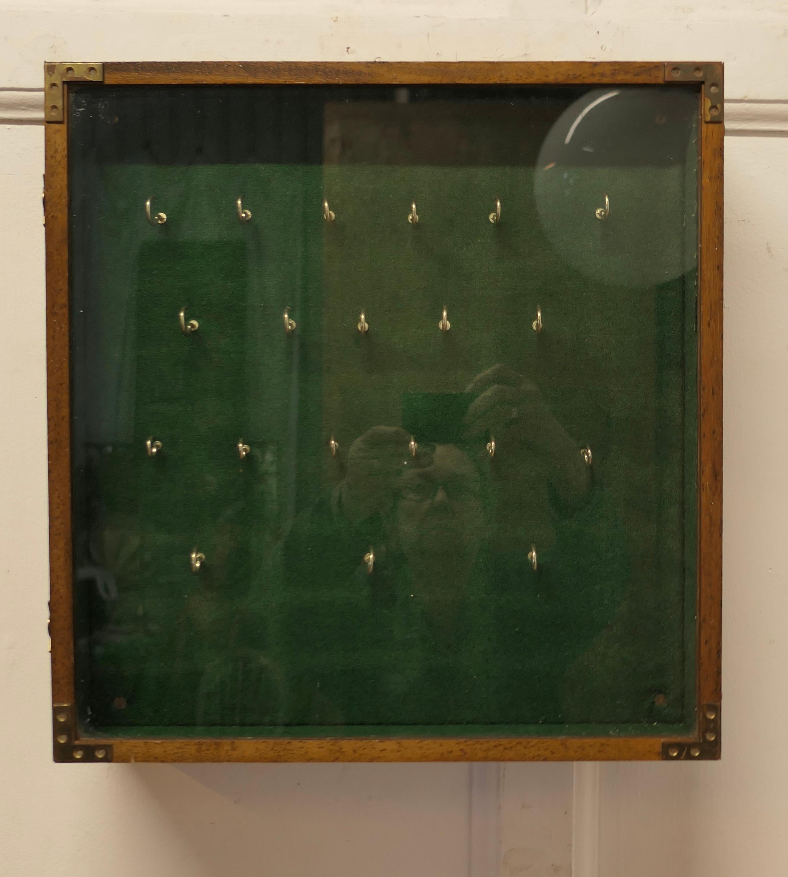 A Campaign Style 20 Hook Wall Hanging Key Cupboard 

A glass fronted key cupboard lined in green base with 12 hooks, the cupboard can be wall hung
The cabinet is in good condition,  it is 16” high 15.5” wide and 4” deep
TFB247