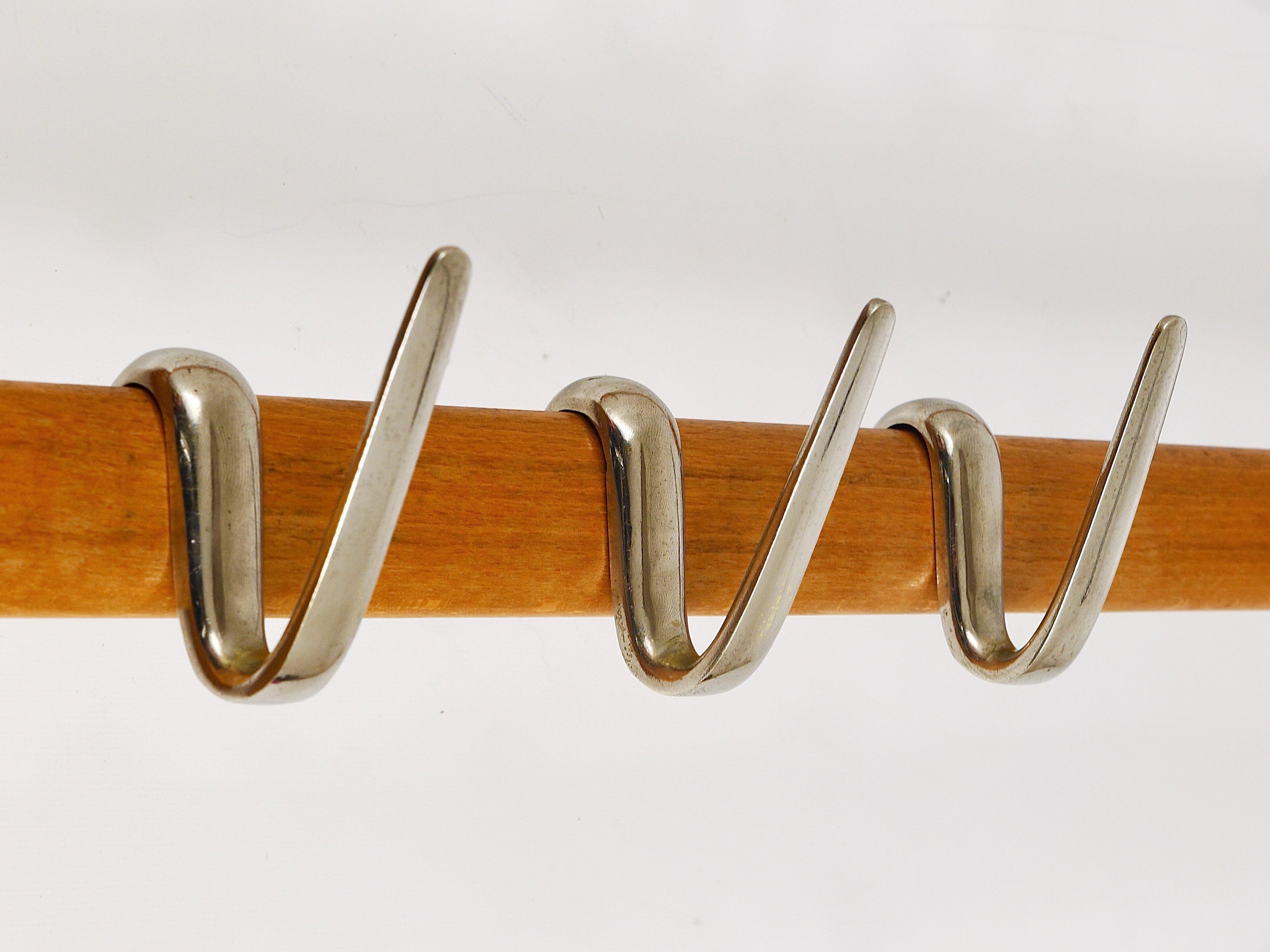 An elegant modernist coat rack from the 1950s, designed and executed by the Austrian designer Carl Auböck. Made of beech with eight rare nickel-plated 