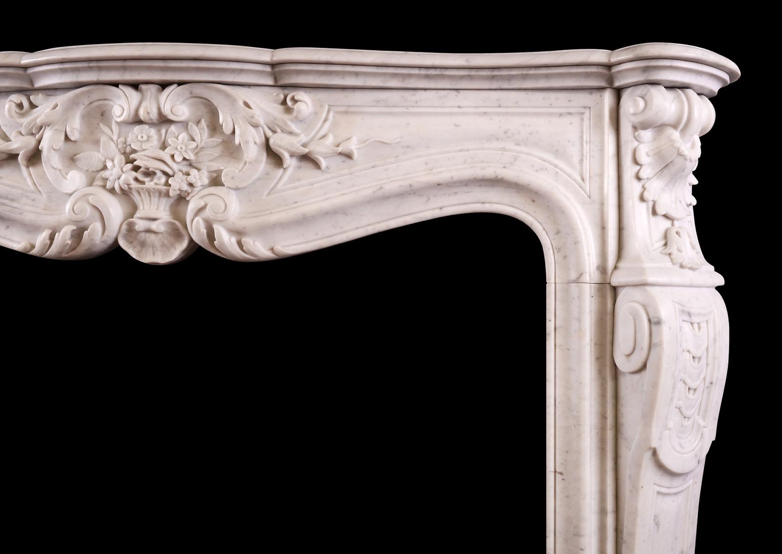 Cheminée en marbre de Carrare du XIXe siècle de style Louis XV. Les montants façonnés avec des feuilles d'acanthe raides à la base, surmontées de rinceaux et de feuillages. La frise est ornée d'un panier de fleurs sculpté au centre, flanqué d'un