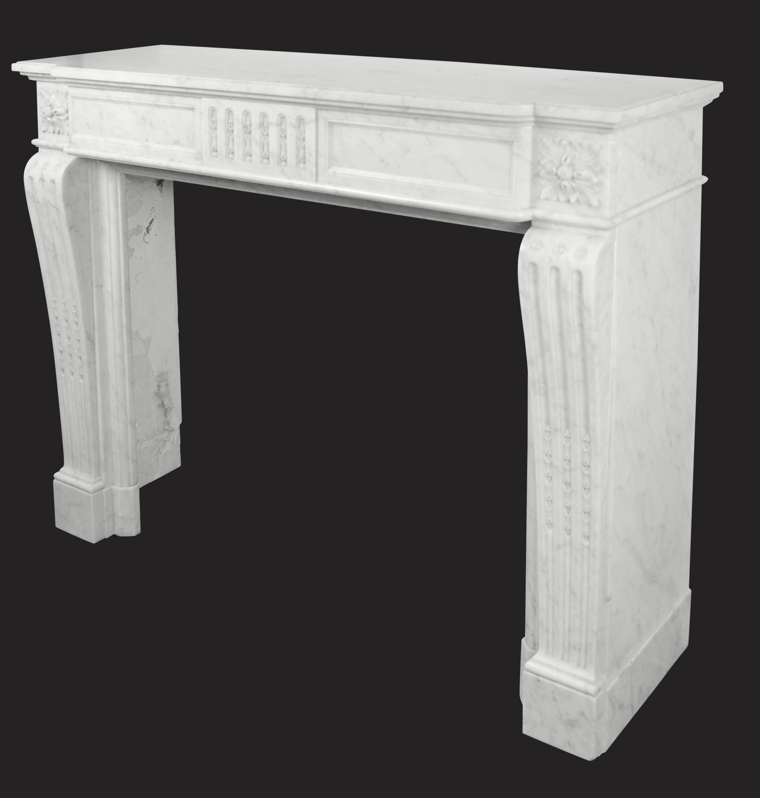 A good Carrara marble French fireplace in the Louis XVI manner. The panelled frieze with fluted detailed centre plaque and foliate corner blocks sits on shaped fluted jambs on simple foot blocks.
Measures: internal width: 37.75
